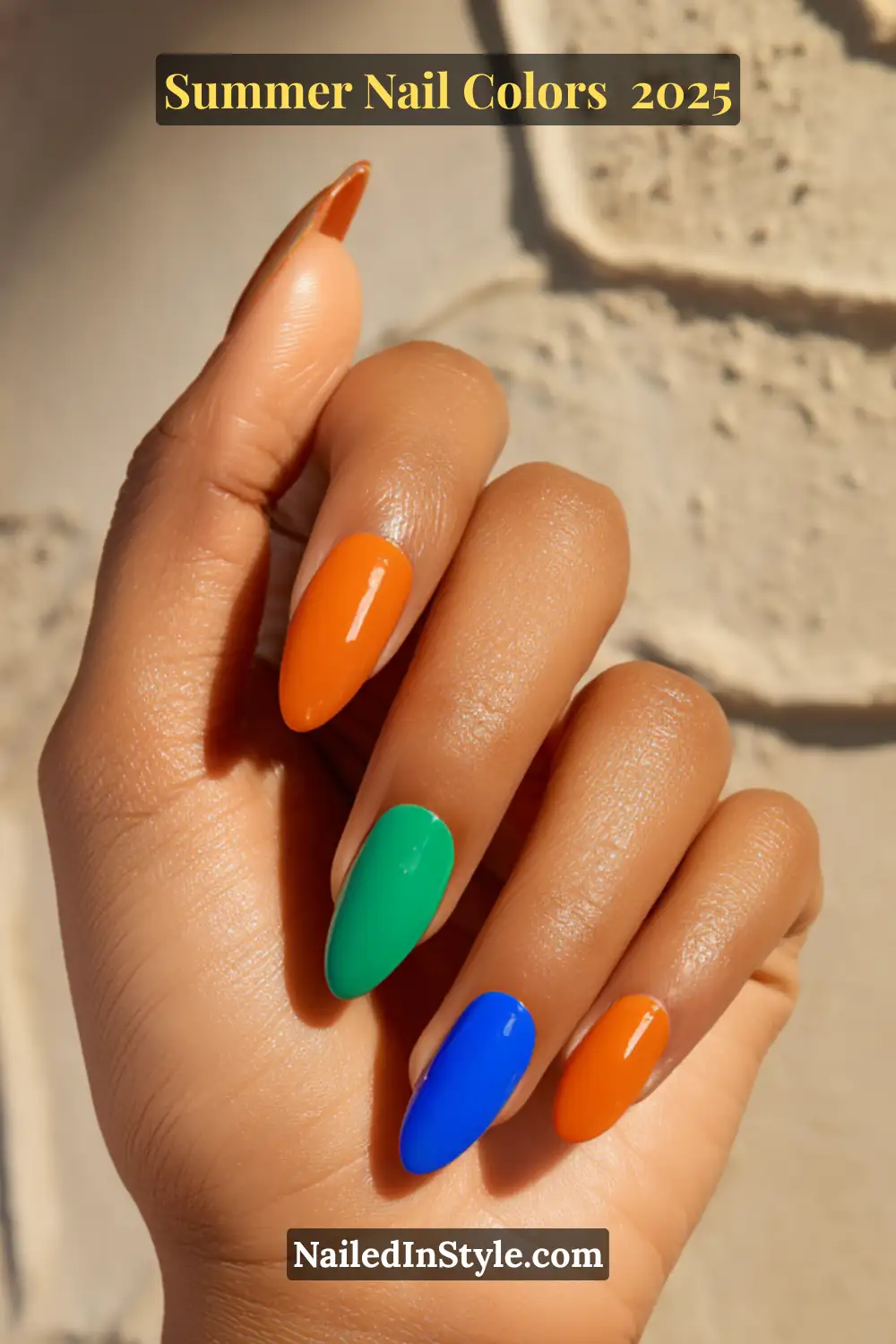 Hottest Summer Nail Colors 2026: Bold, Breezy & On-Trend 9 Close-up of medium-toned hand with nails painted in tangerine orange, pistachio green, and cobalt blue—bold summer shades for olive skin.