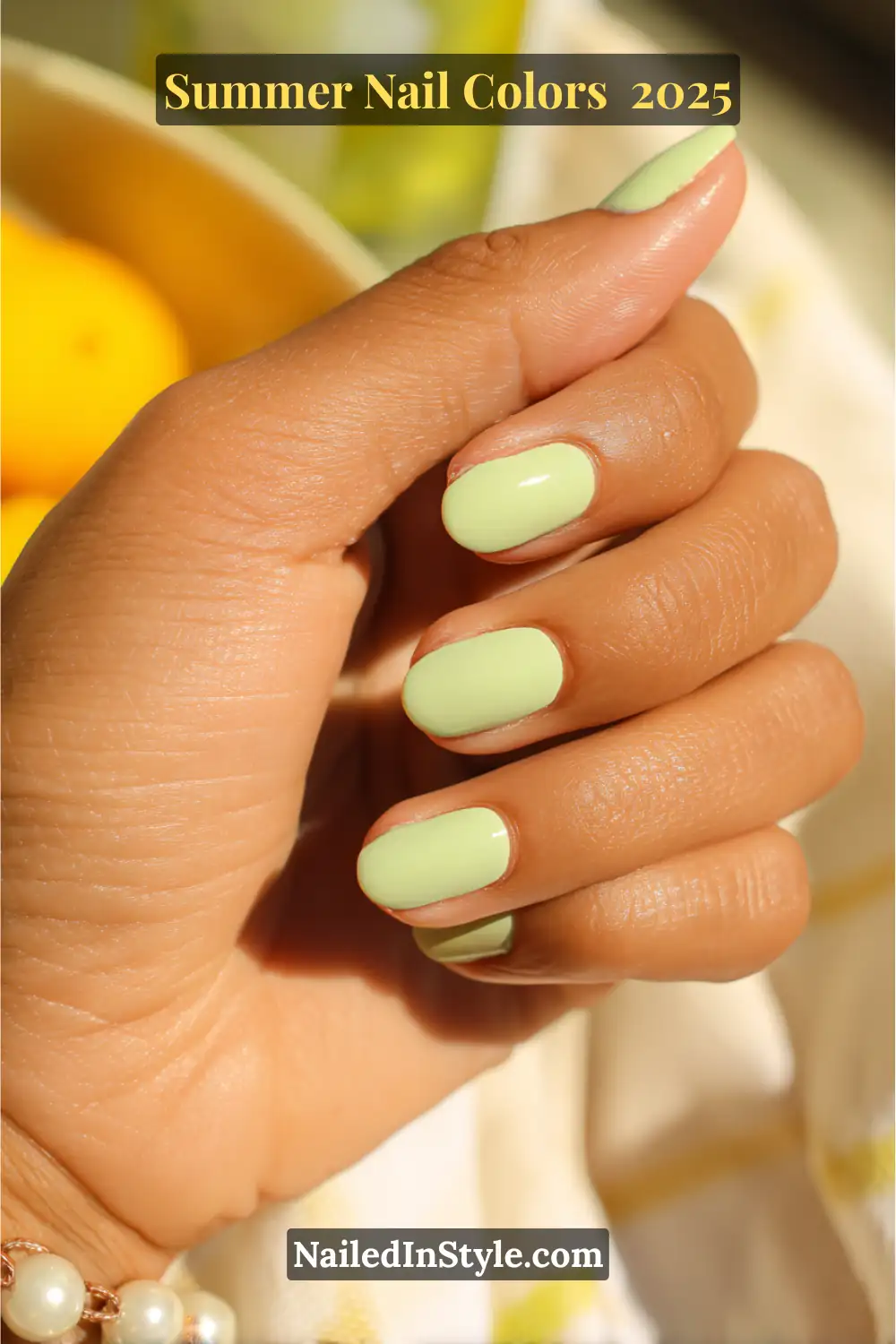 Hottest Summer Nail Colors 2026: Bold, Breezy & On-Trend 19 A close-up of a hand with neatly manicured nails painted in a creamy pistachio green shade, glowing in natural sunlight.
