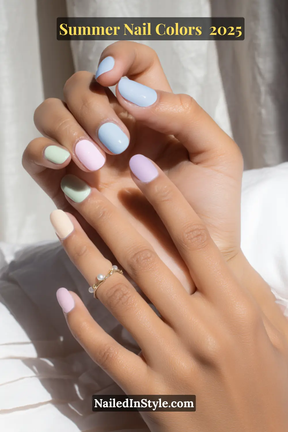 Hottest Summer Nail Colors 2026: Bold, Breezy & On-Trend 4 Close-up of hands with short rounded nails painted in soft pastel shades: baby blue, lavender, mint green, peach, and pink.