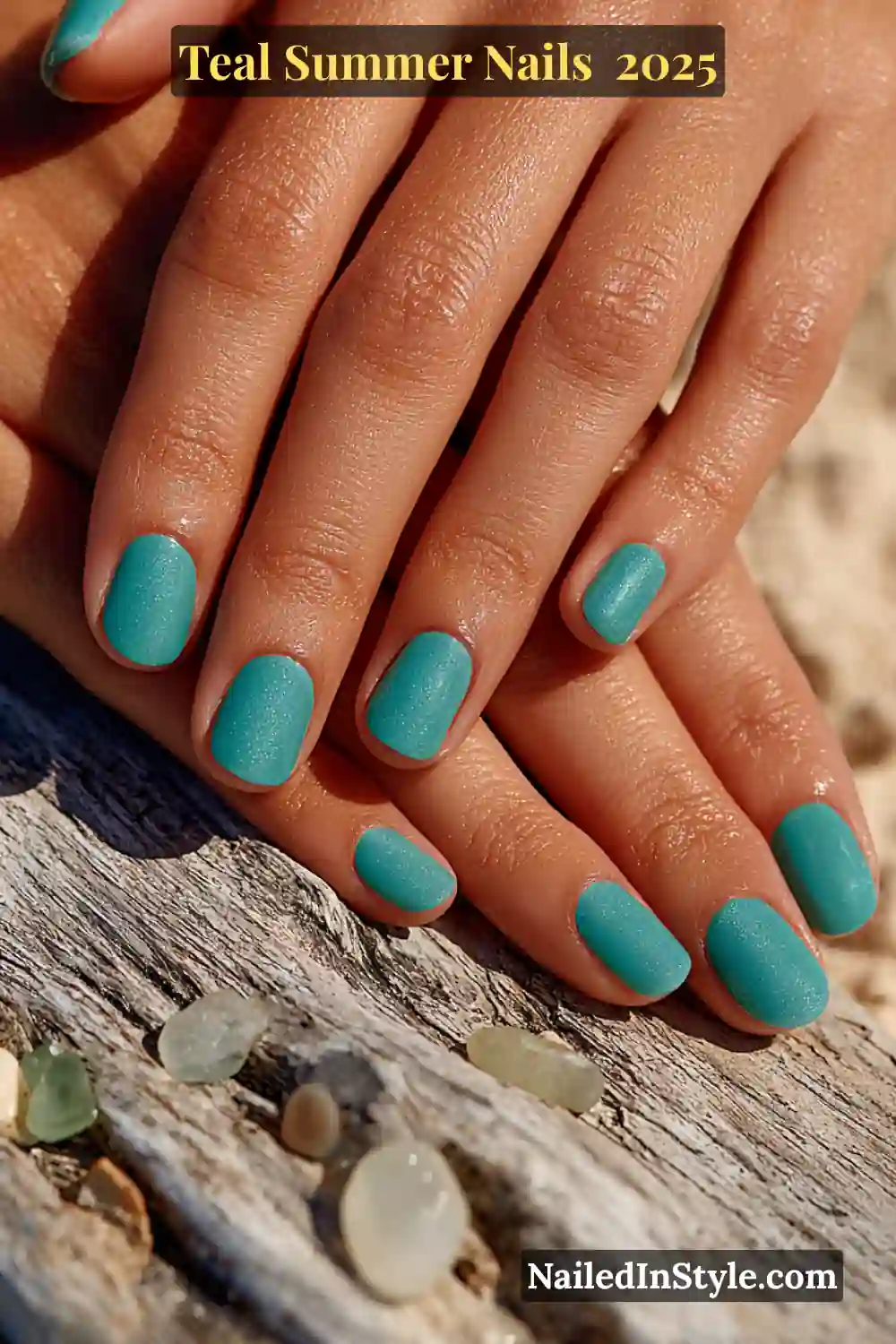 Teal Summer Nails 2025 Two natural female hands with teal short square nails resting on driftwood with sea glass scattered around, captured in soft summer sunlight