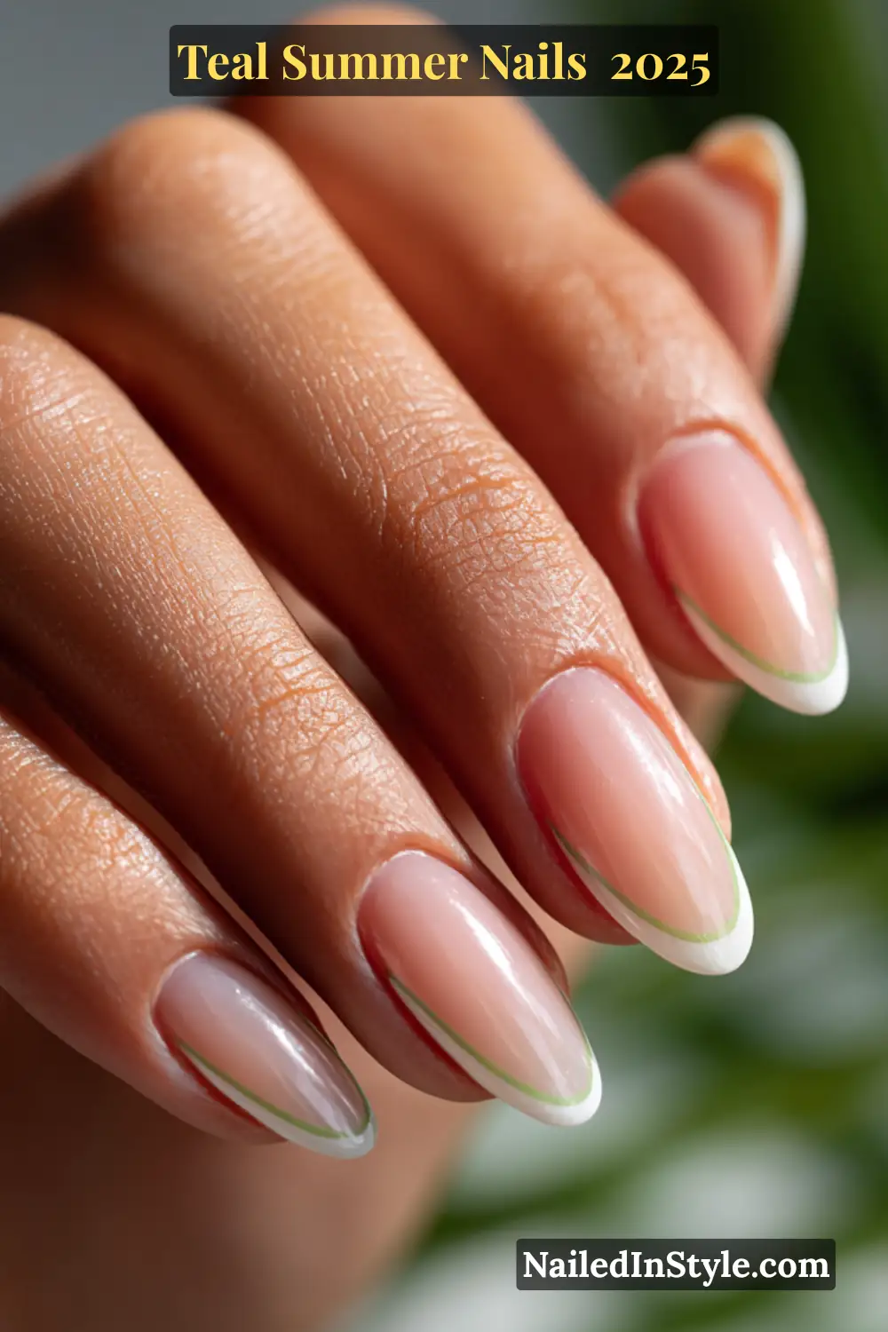 Editorial close-up of almond-shaped natural nails with a nude base and thin white and teal-green micro French tips on a medium-toned hand