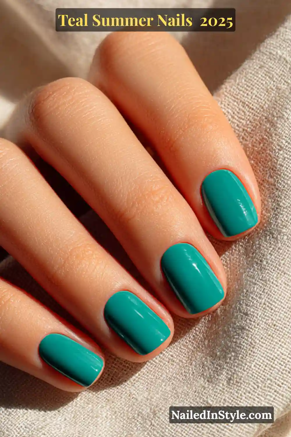 Close-up of a fair-skinned female hand with glossy teal short square nails, resting on natural beige linen in sunlight