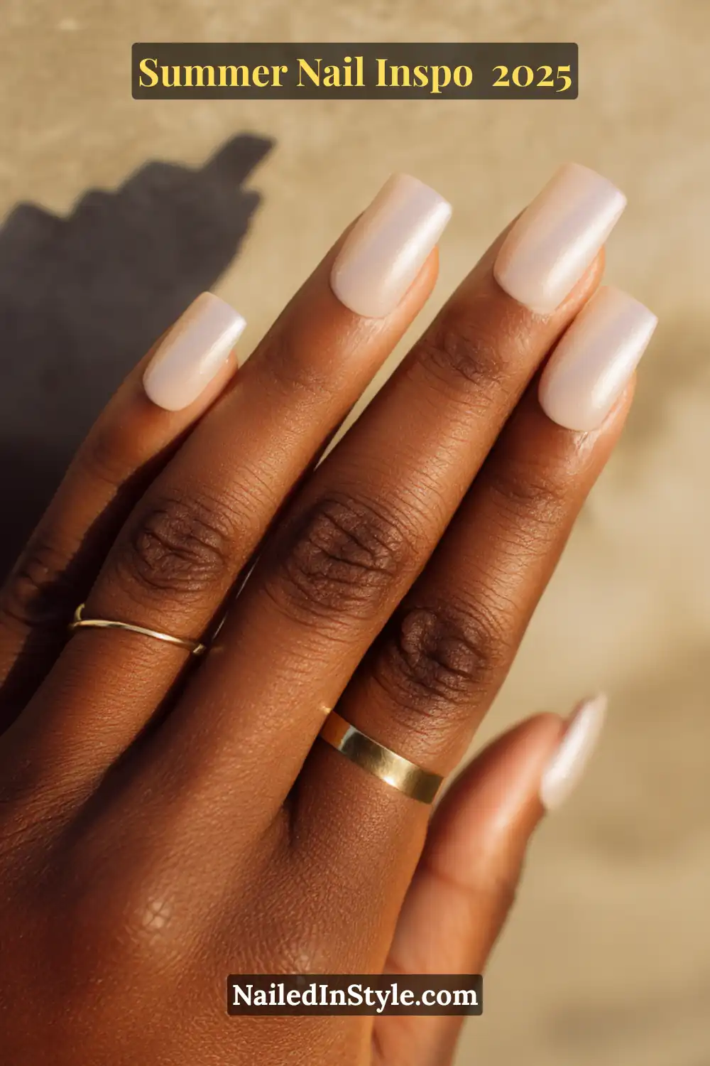 Close-up of a hand with square-shaped nails in a soft vanilla chrome finish, featuring a subtle shimmer overlay on deep skin.