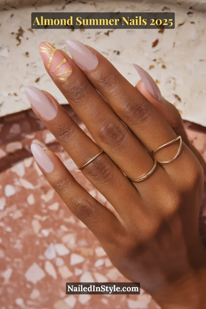 Almond-shaped nails with a nude pink base and a single gold line accent design on a dark-skinned hand
