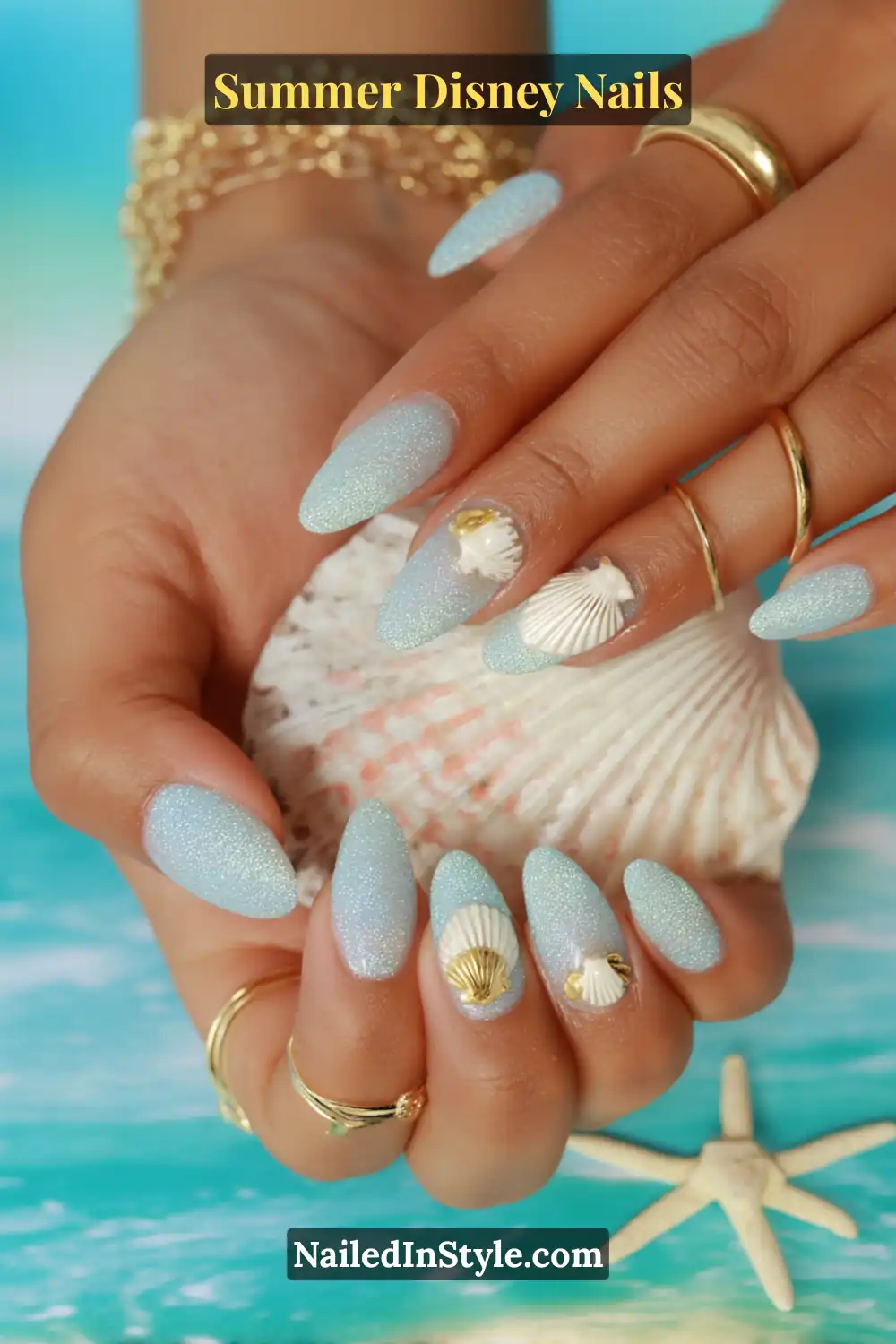 Almond-shaped aqua glitter nails with 3D white and gold seashell charms.