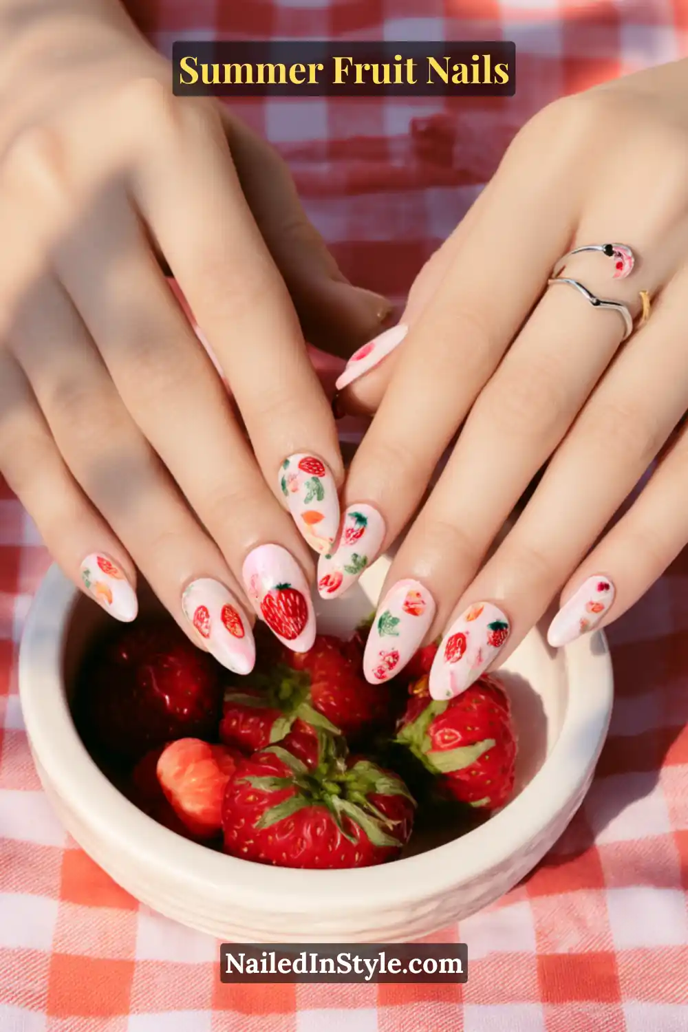 Playful summer nail art with a soft pink base, decorated with red strawberry and raspberry patterns accented by green leaves.