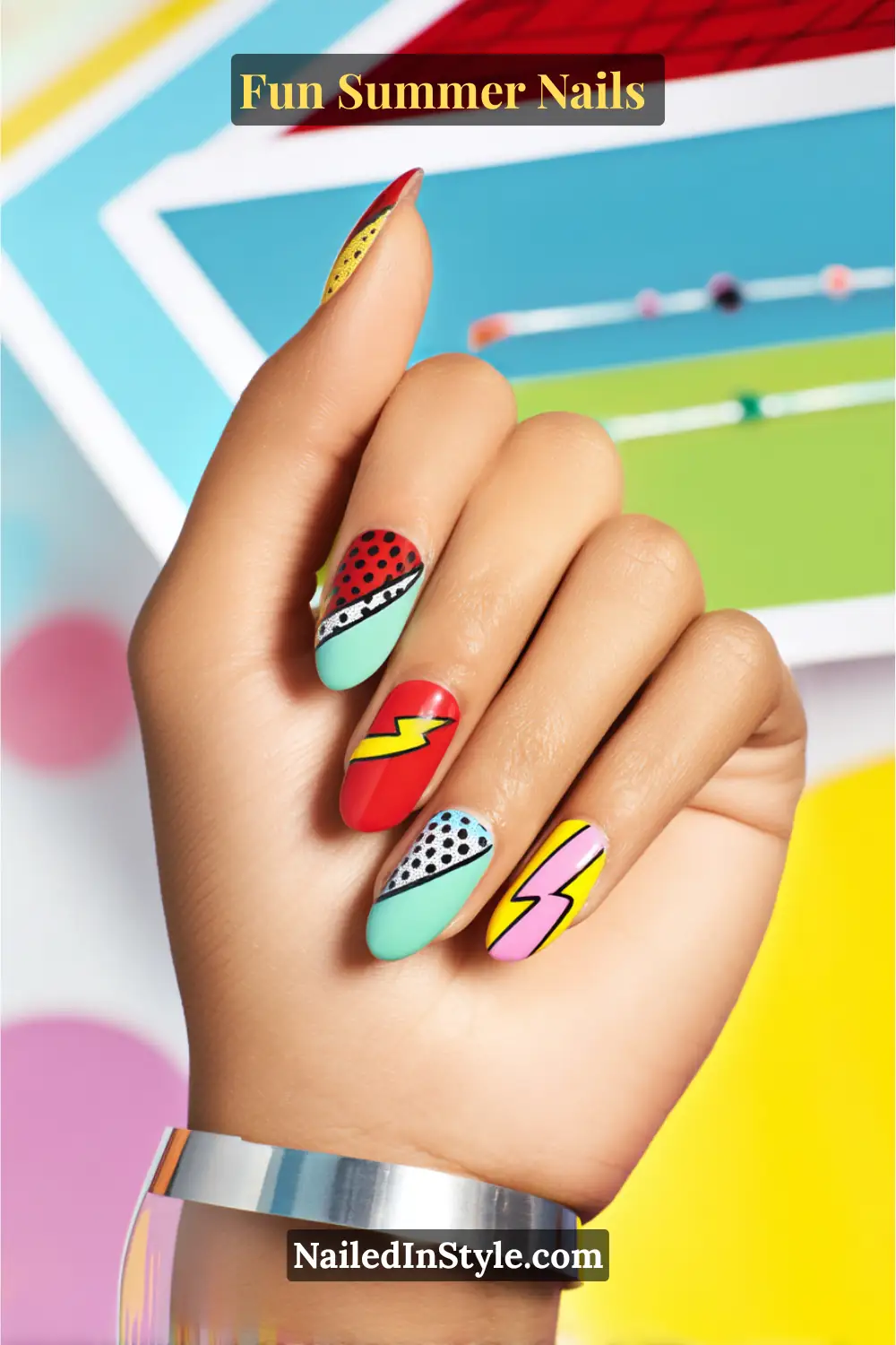 Hand with cartoon pop summer nails featuring comic-inspired designs, bold colors, lightning bolts, and dotted accents.