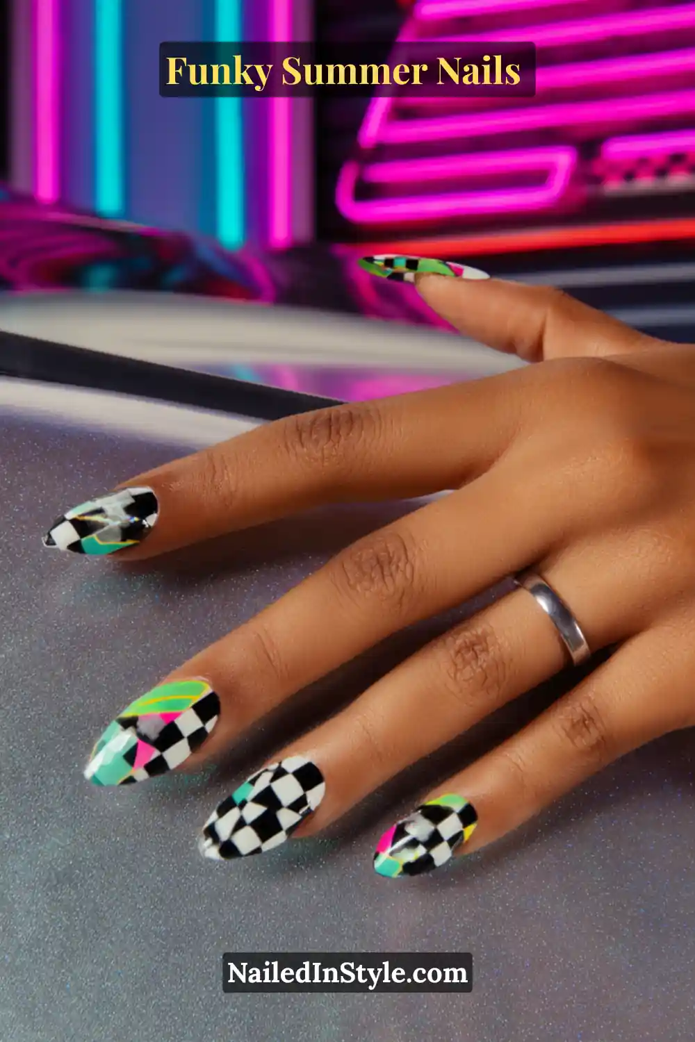 Close-up of almond-shaped nails featuring bold black-and-white checkerboard patterns mixed with neon accents in green, pink, and yellow. A funky, high-contrast design with a modern edge.