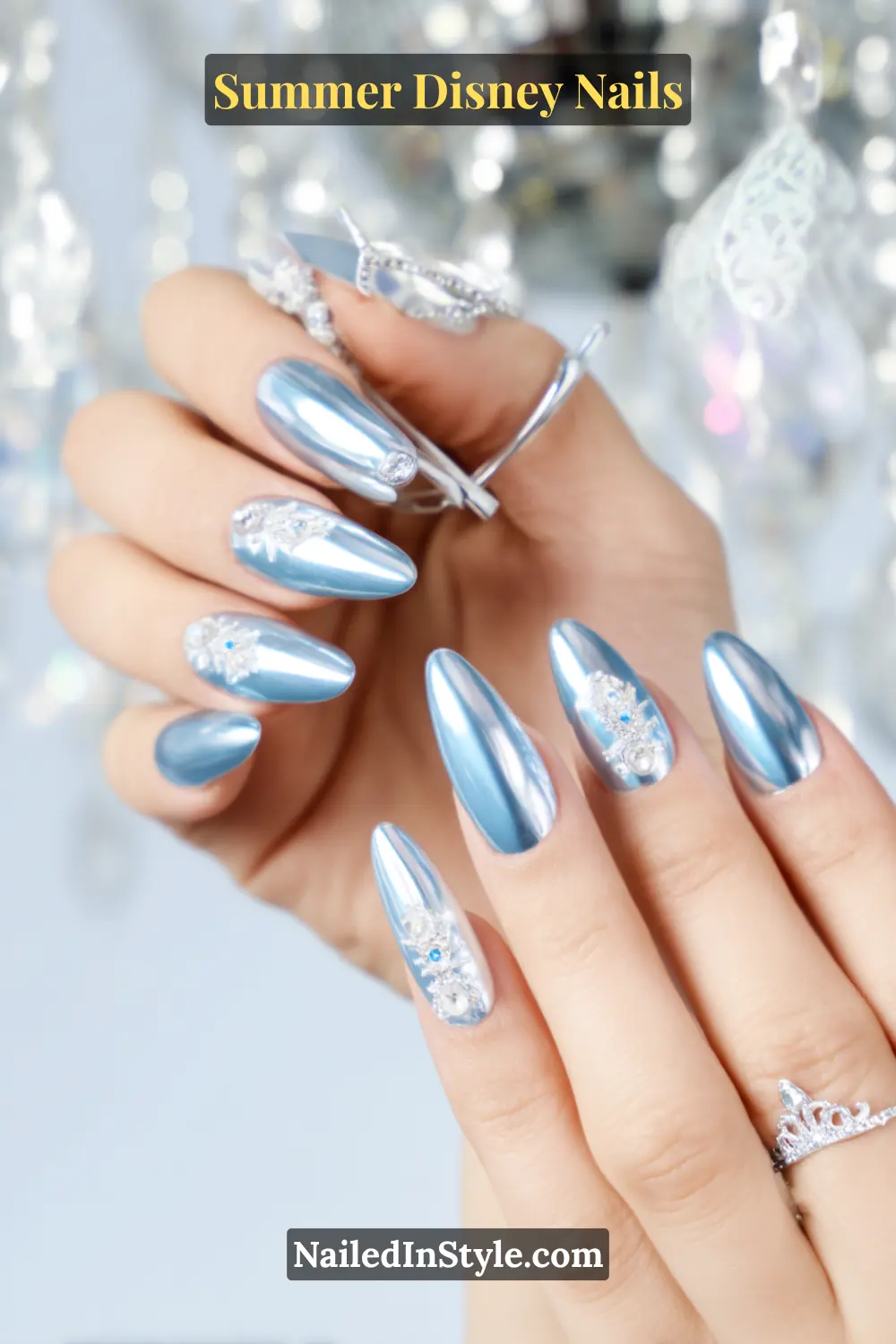 Almond-shaped icy blue chrome nails with 3D tiara and crystal accents.
