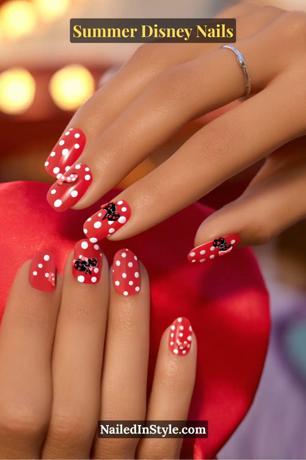 Short square nails painted red with white polka dots and tiny black Minnie Mouse bows.