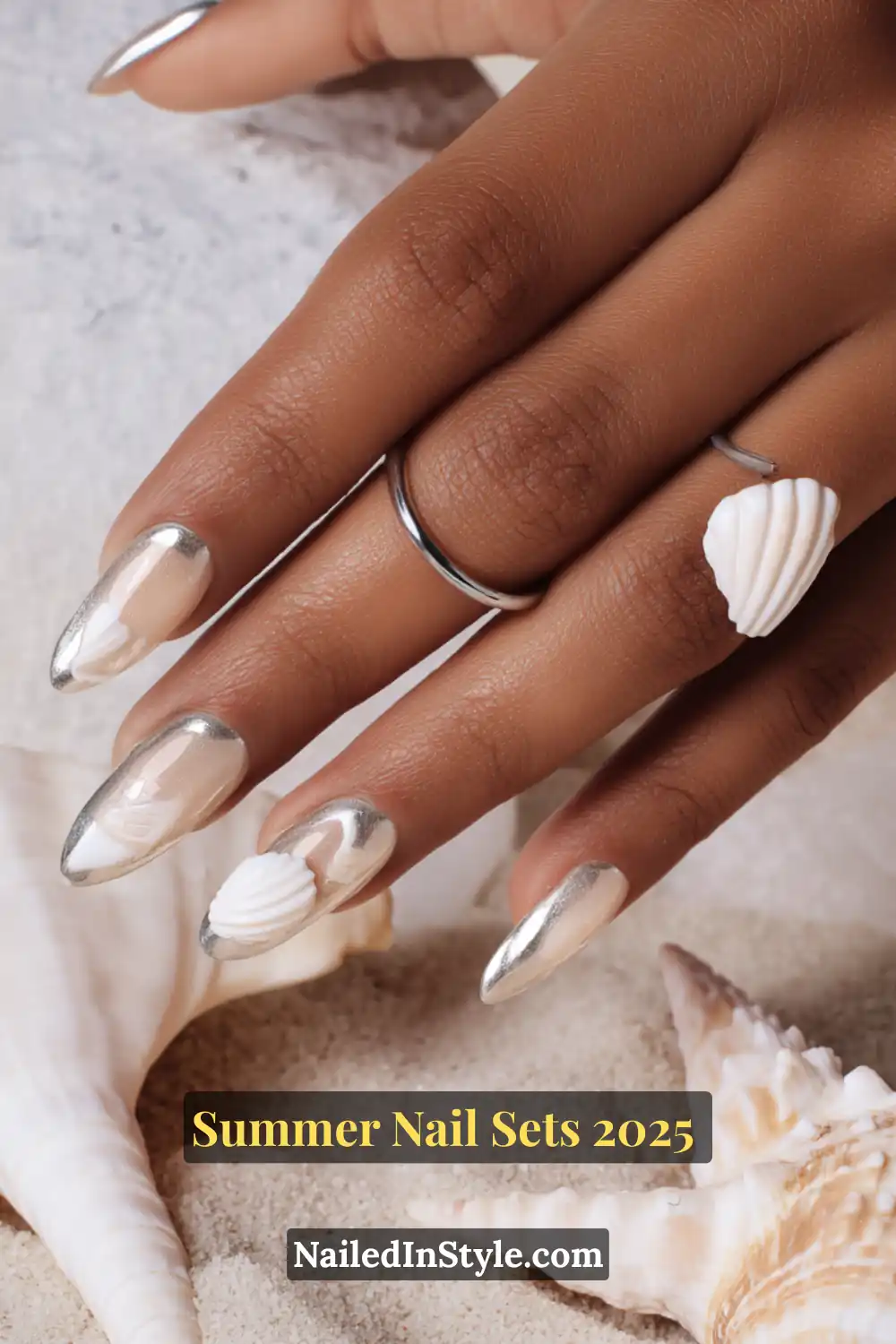 Stunning Summer Nail Sets You’ll Want This Season 6 Almond-shaped nails with cloud white base, chrome tips, and 3D seashell nail art on sandy beach background