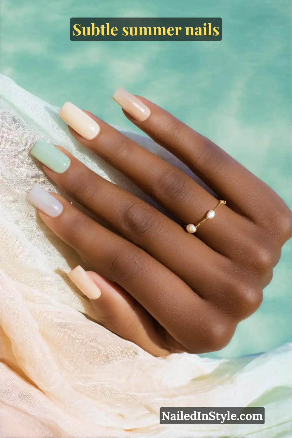 Square-shaped nails painted in sandy beige, seafoam green, and soft nude shades with a delicate pearl-accent ring, styled against a breezy summer backdrop.