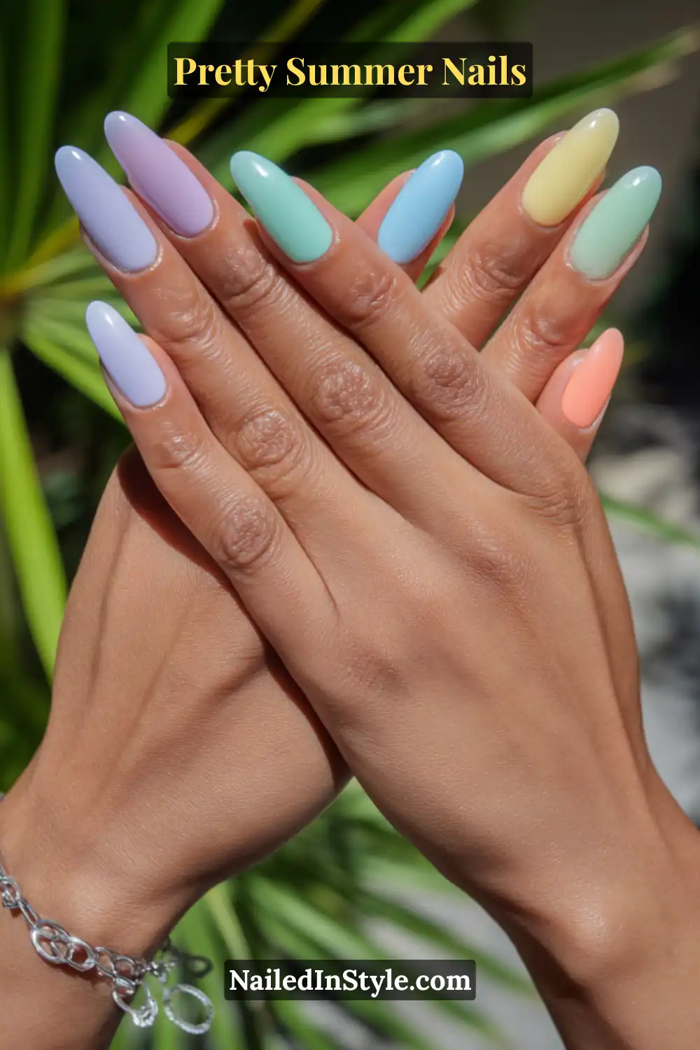 Hands with almond-shaped nails painted in pastel rainbow shades (lavender, mint, blue, yellow, peach).