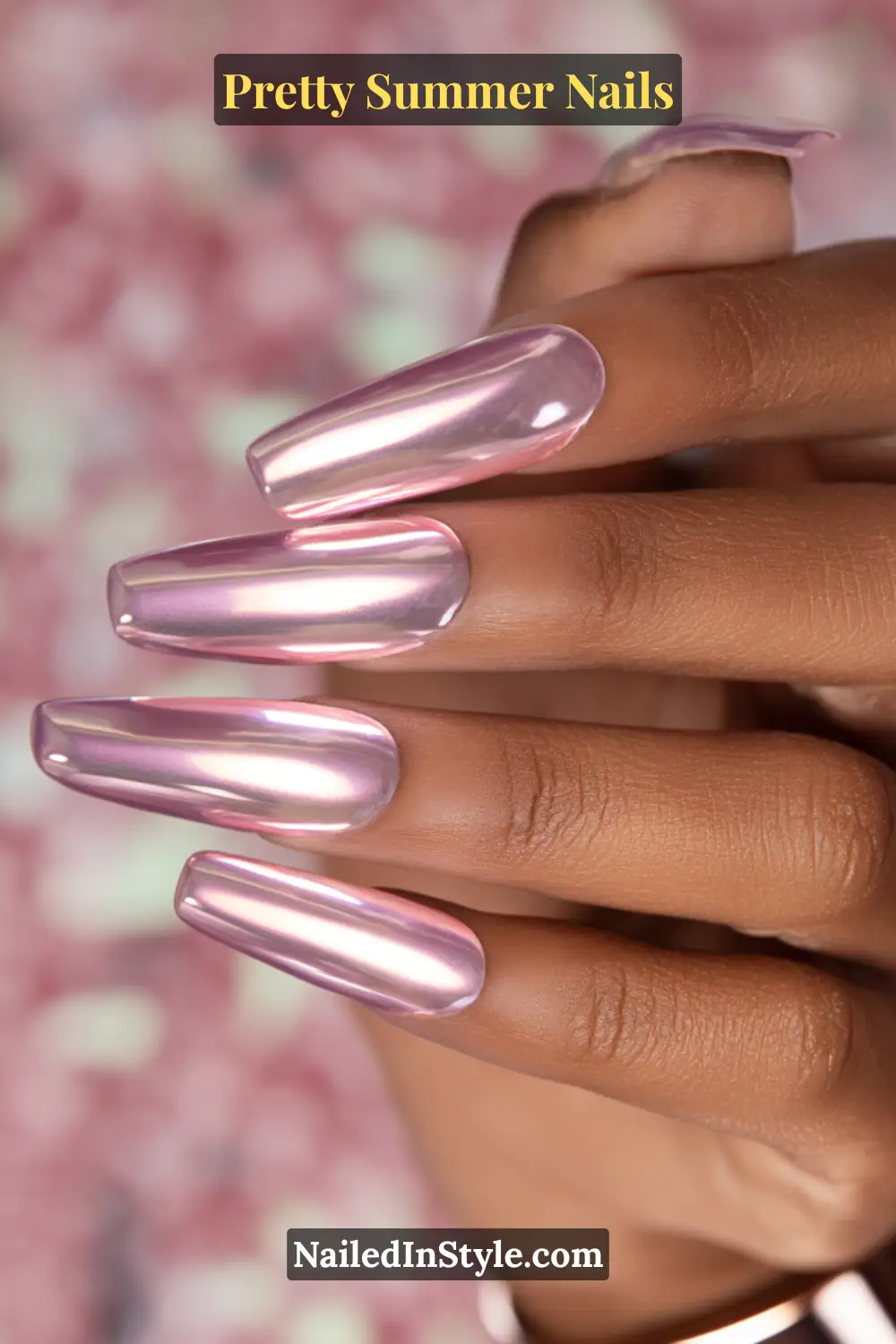 Close-up of long coffin-shaped nails in ultra-glossy pink chrome polish on deep skin tone.