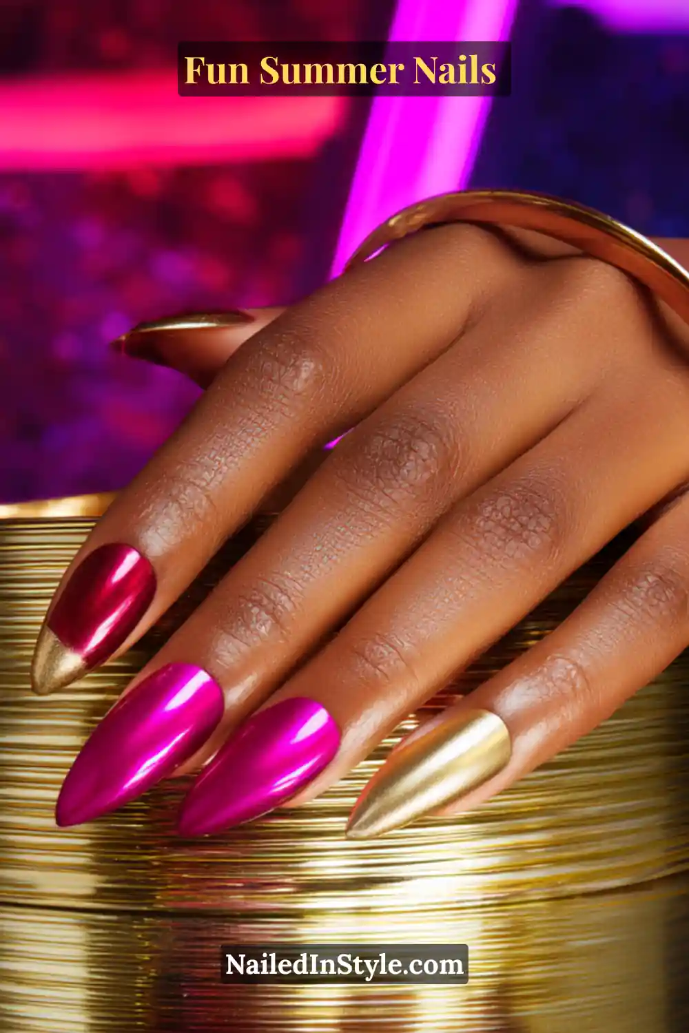Hand with deep skin tone featuring vibrant fuchsia and metallic gold nails, creating a bold, glamorous summer manicure.