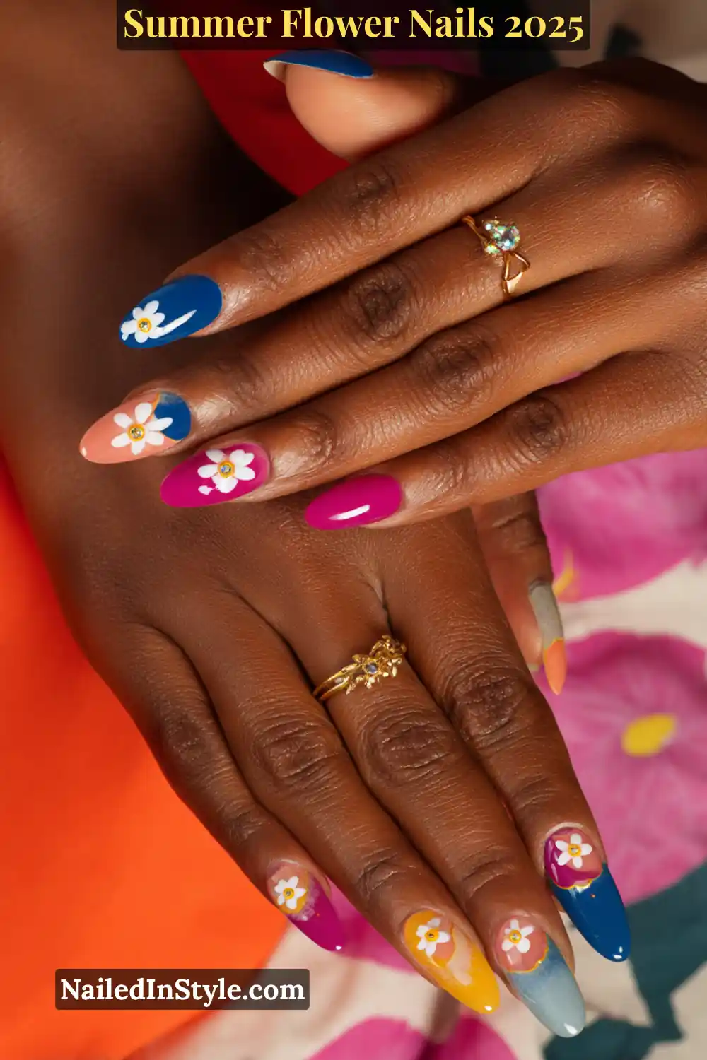 Bold flower nail art with magenta, yellow, cobalt blue, and peach tones on deep skin.