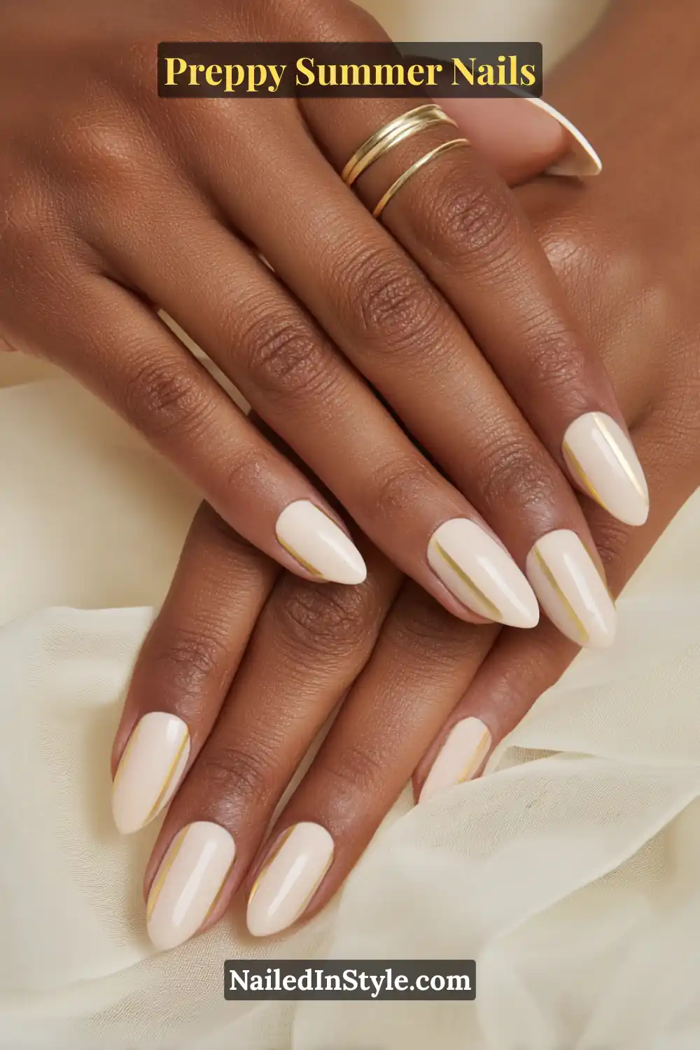 Hands with glossy cream nails featuring thin gold stripe accents on deep skin tone.