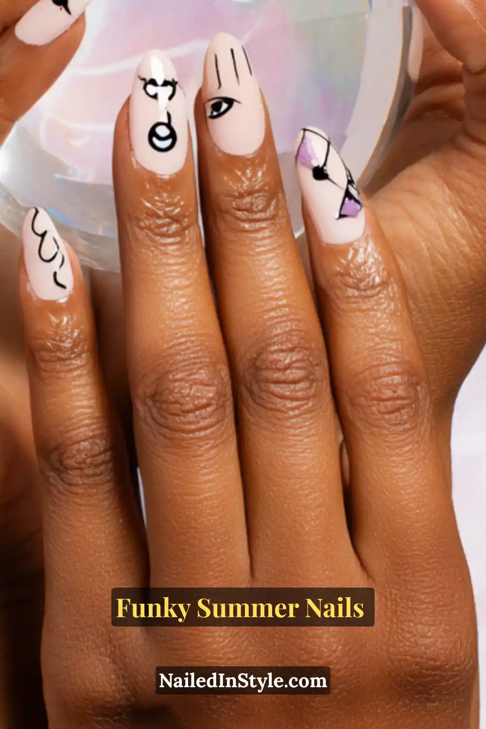 Close-up of almond-shaped nails painted with a soft nude base and decorated with abstract black line sketches, including faces, eyes, and whimsical doodles. Minimal yet artsy design with a funky edge.
