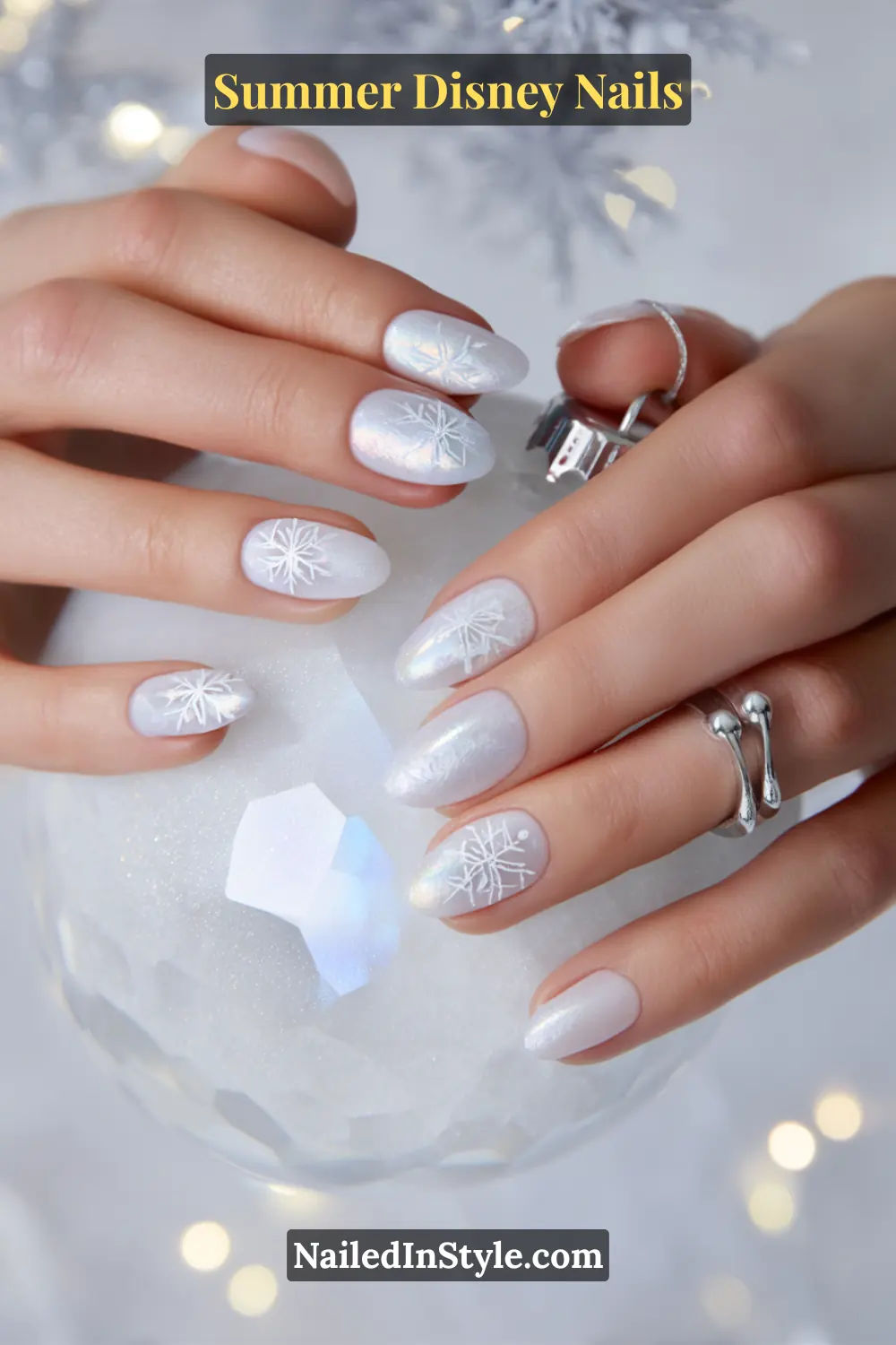 Almond-shaped nails in white shimmer with delicate silver snowflake designs.