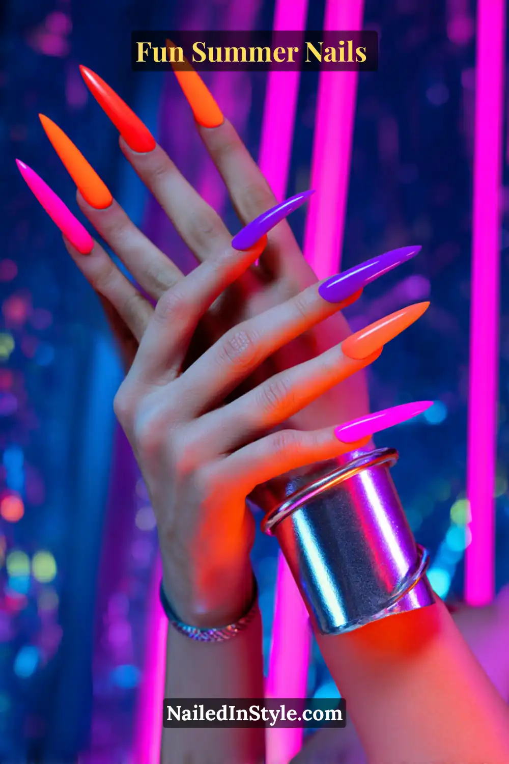 Hands with extra-long neon nails in orange, purple, and fuchsia, glowing under UV light with a futuristic vibe.