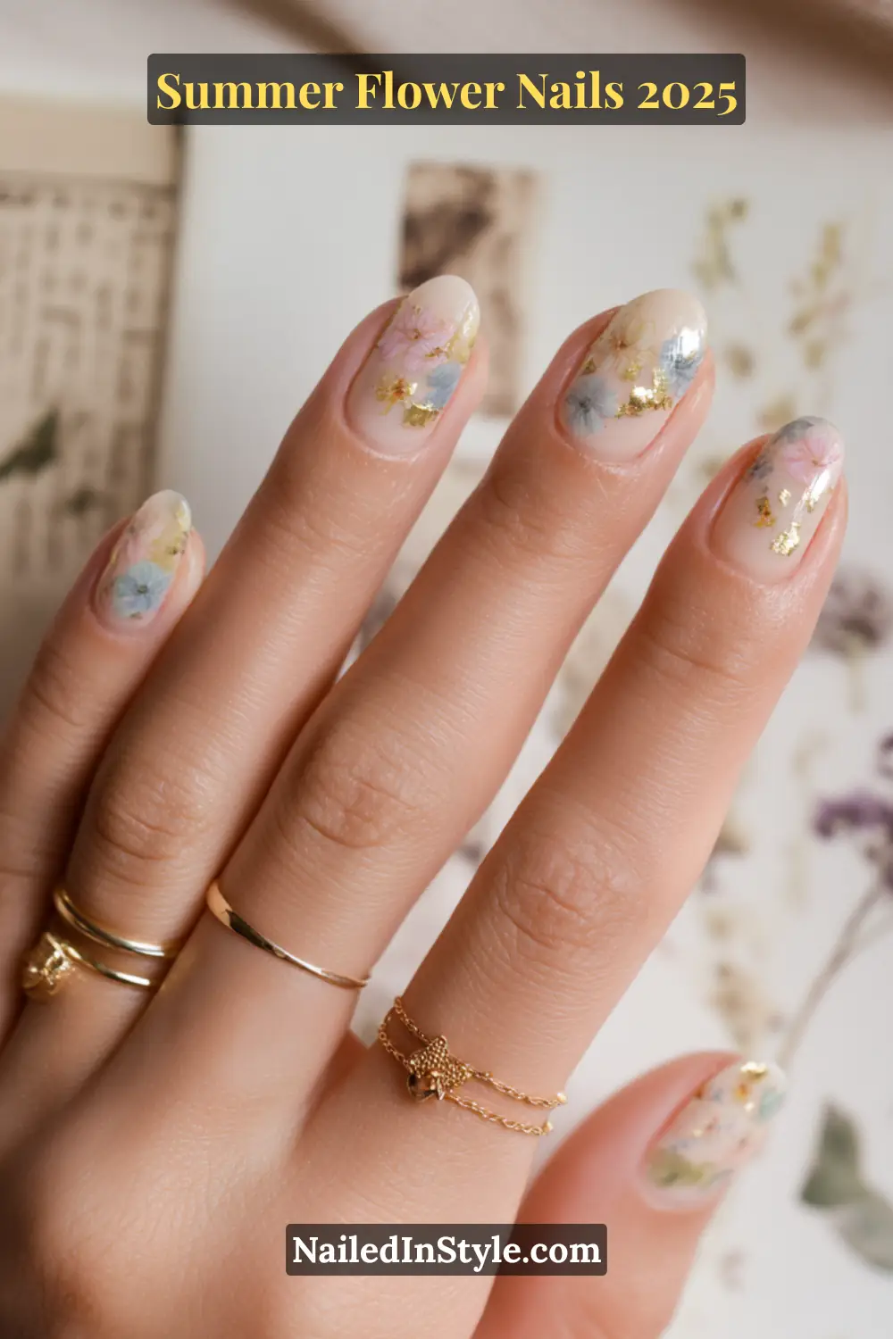 Rounded short nude nails with pastel floral decals and gold foil accents.