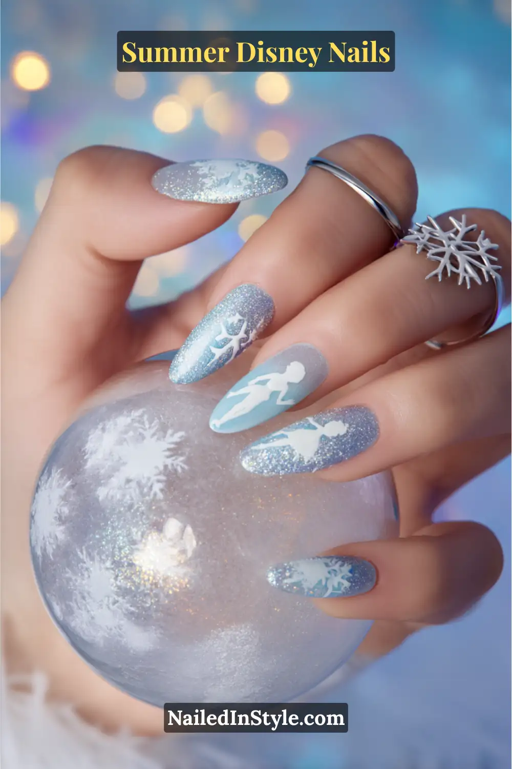 Long almond nails in icy blue and silver glitter with snowflake accents and white Elsa silhouette decals.