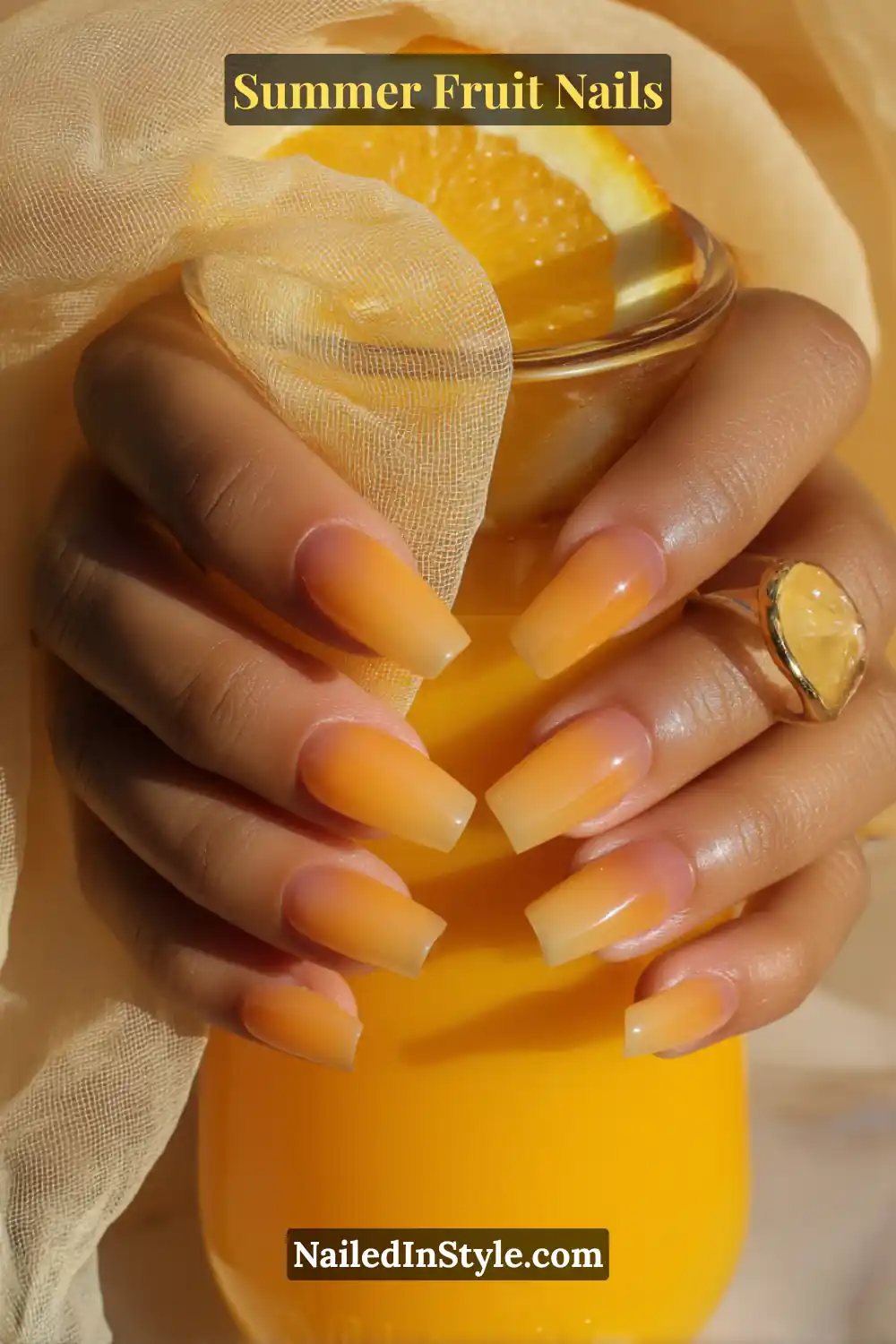 Square-shaped nails with a smooth yellow-to-orange ombré gradient, complementing a glass of orange juice.