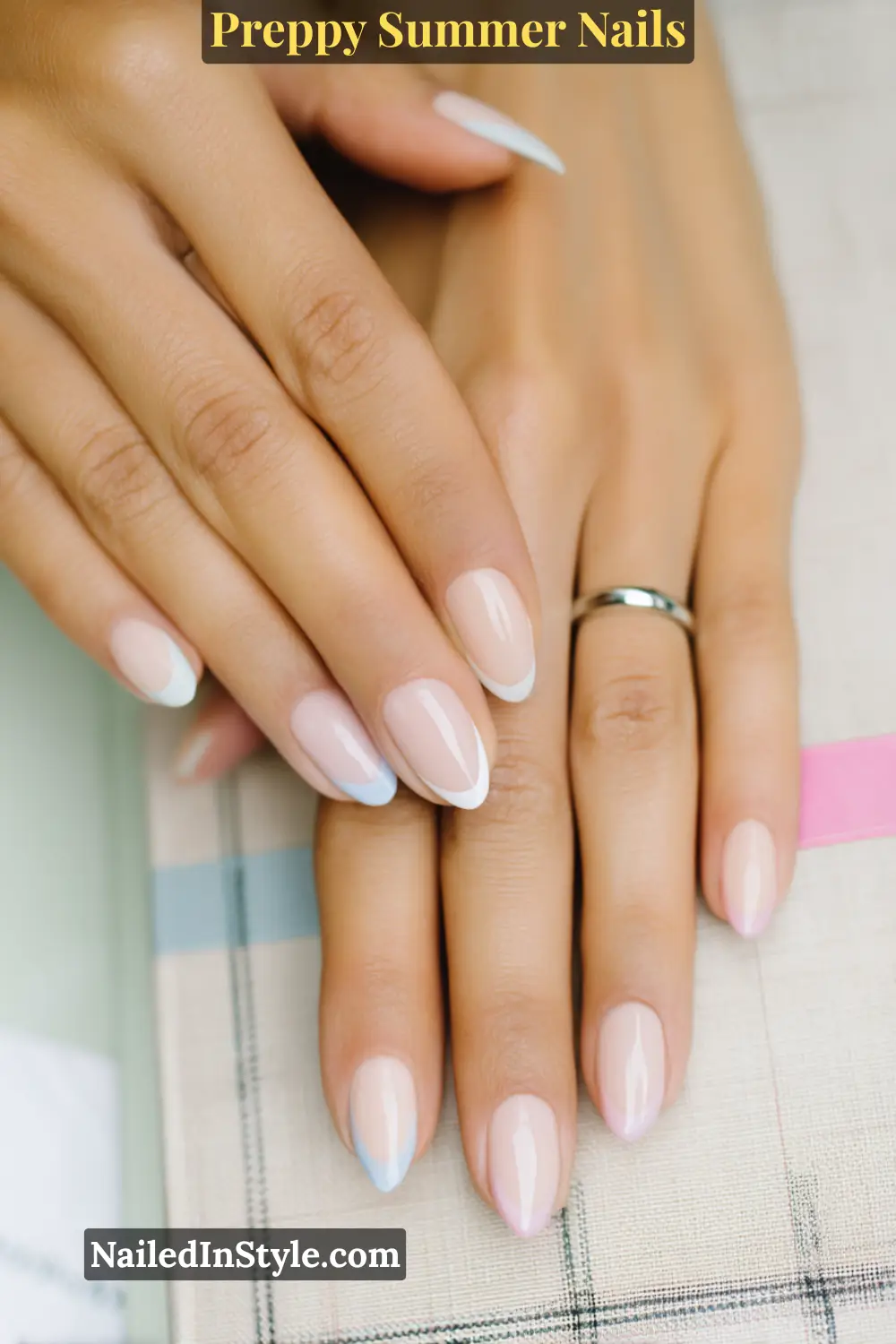 Hands with nude nails featuring white and baby blue French tips on a glossy finish.