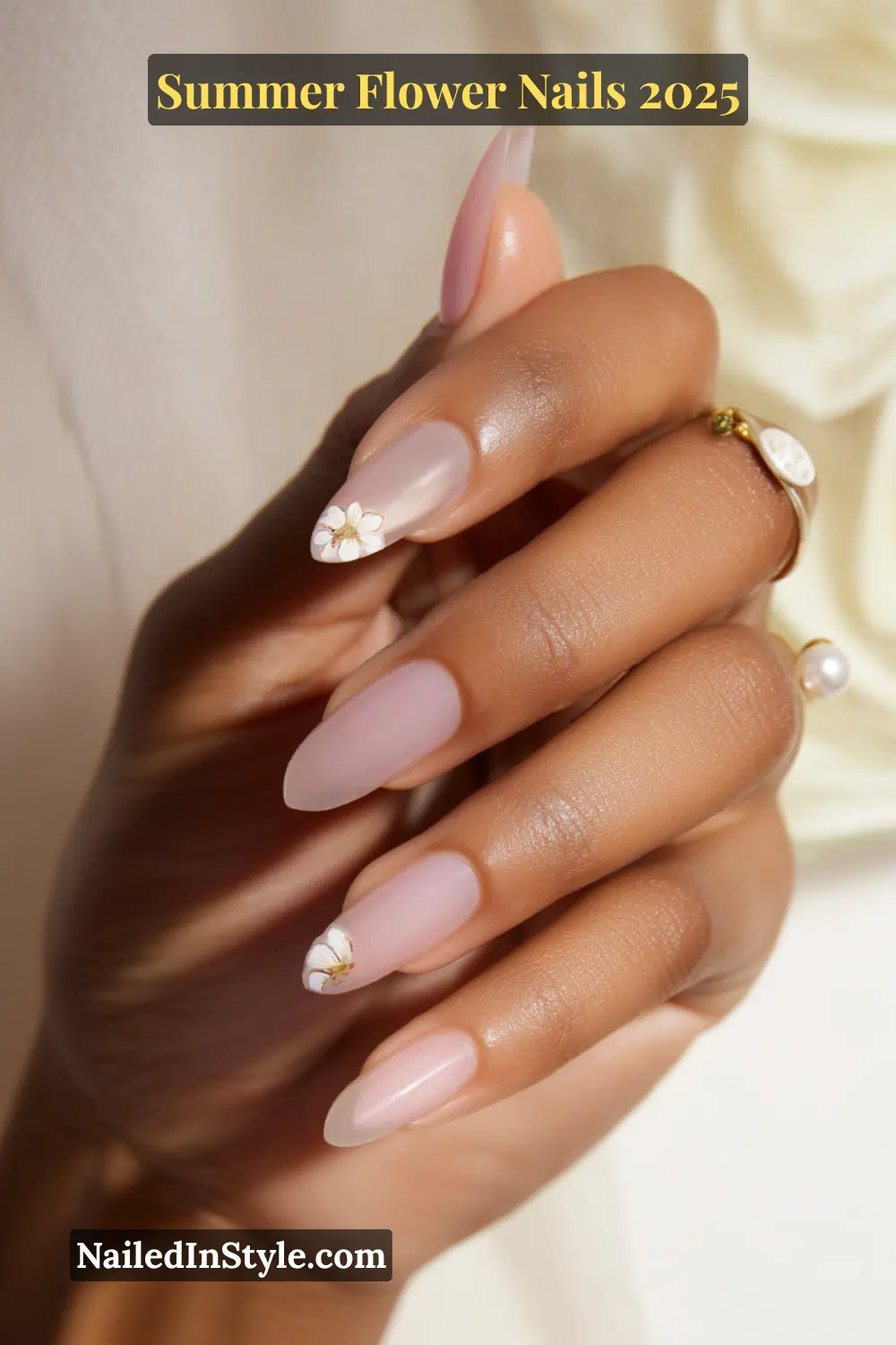 Almond nude acrylic nails with soft blush undertones and delicate single floral accents on ring and index fingers