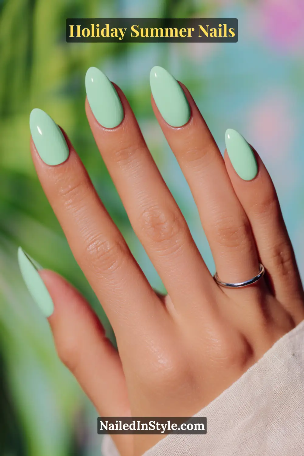 Hand with mint green glossy nails, styled against a tropical background, giving fresh summer vibes.