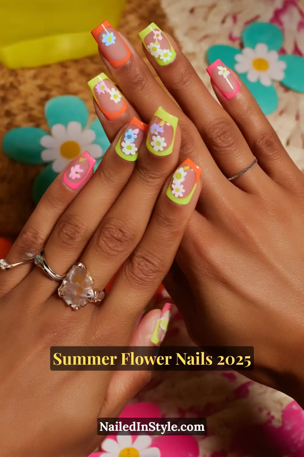 Square nails with neon French tips and white flower stickers on a sheer nude base.