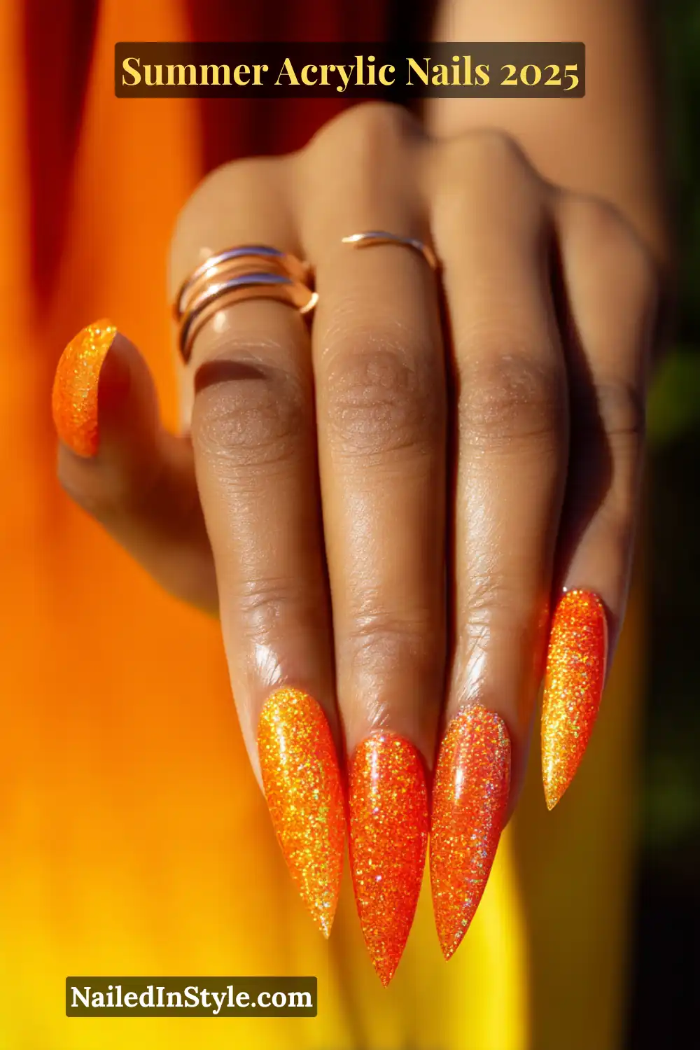 Summer Acrylic Nails 2026: Bold, Beautiful & Built to Last 12 Hand with long stiletto-shaped acrylic nails in neon orange, featuring a glitter fade effect on each nail
