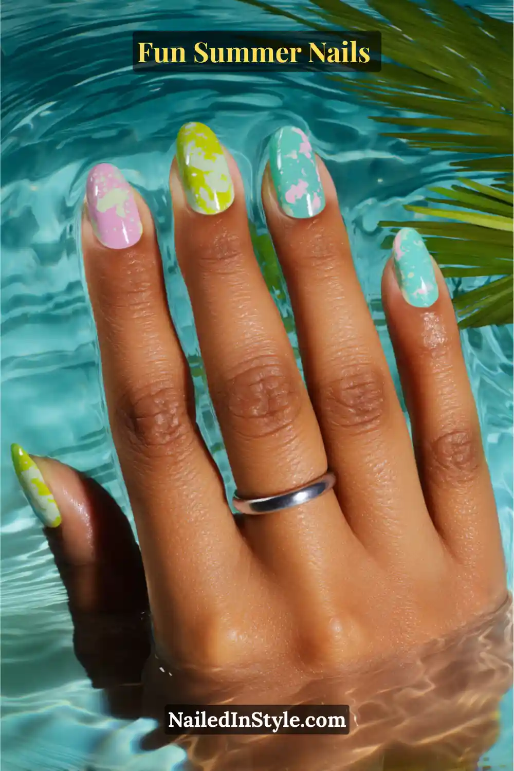 Hand with neon splash summer nails featuring aqua, pink, and lime green splash effect designs over pastel bases.