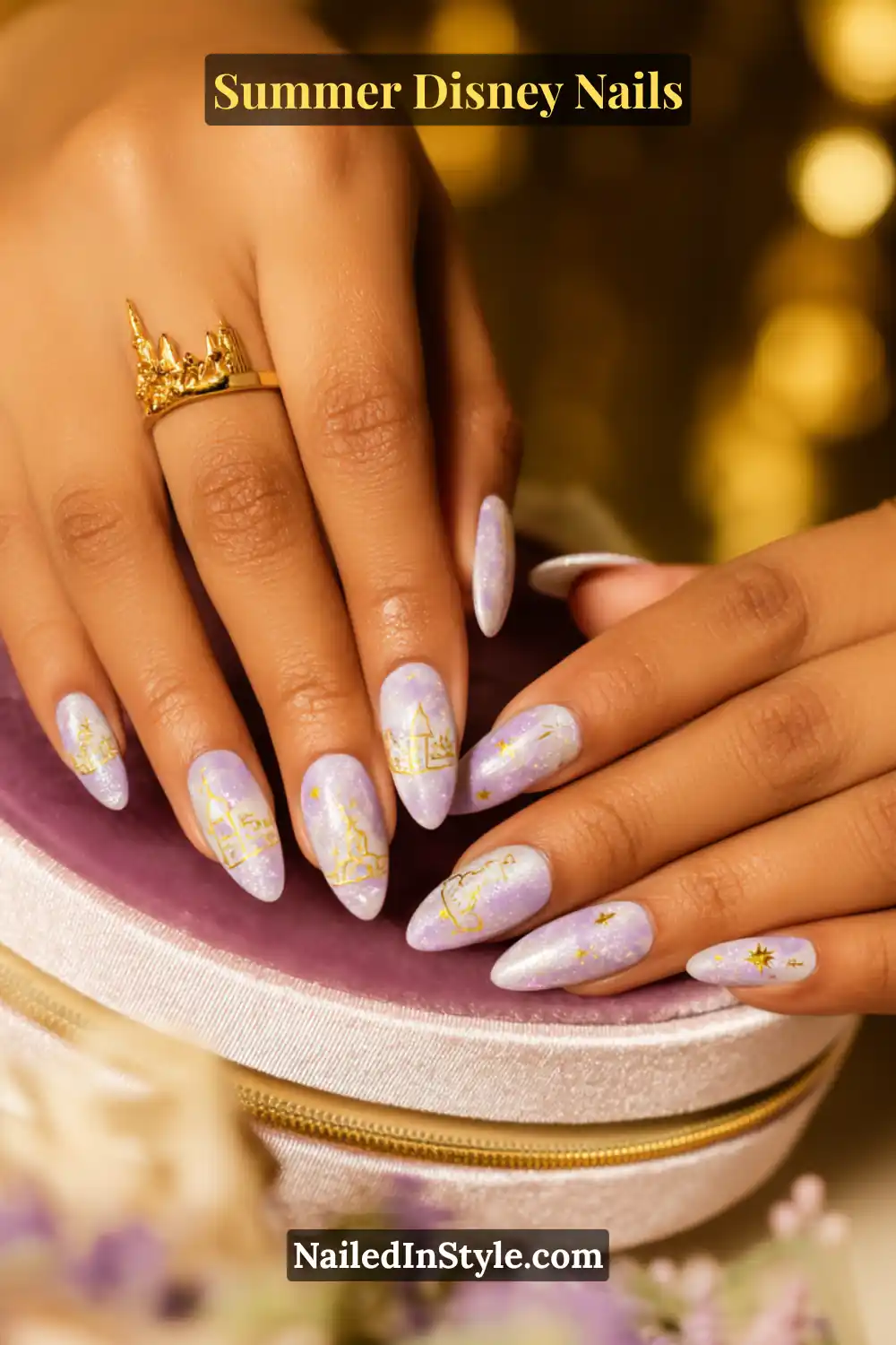 Long almond nails in shimmering lavender with gold Disney castle and star accents, perfectly complementing olive skin.
