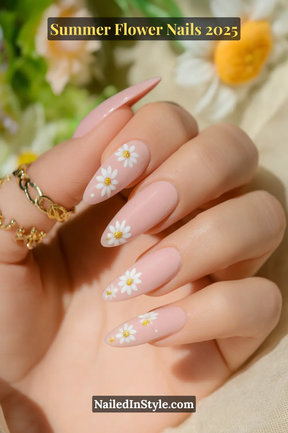Pastel pink almond-shaped nails with white daisy flower designs and gold accents.