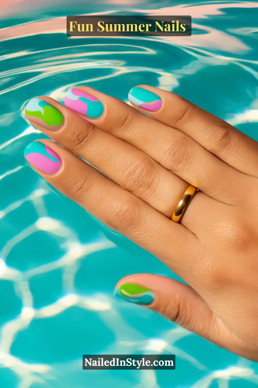 Hand with fun summer nails featuring aqua, hot pink, and lime green splash-inspired designs over a glossy base.