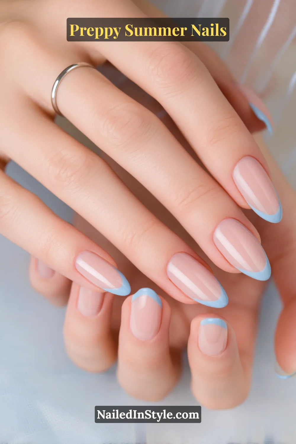 Hands with nude nails featuring crisp baby blue French tips on a glossy base.