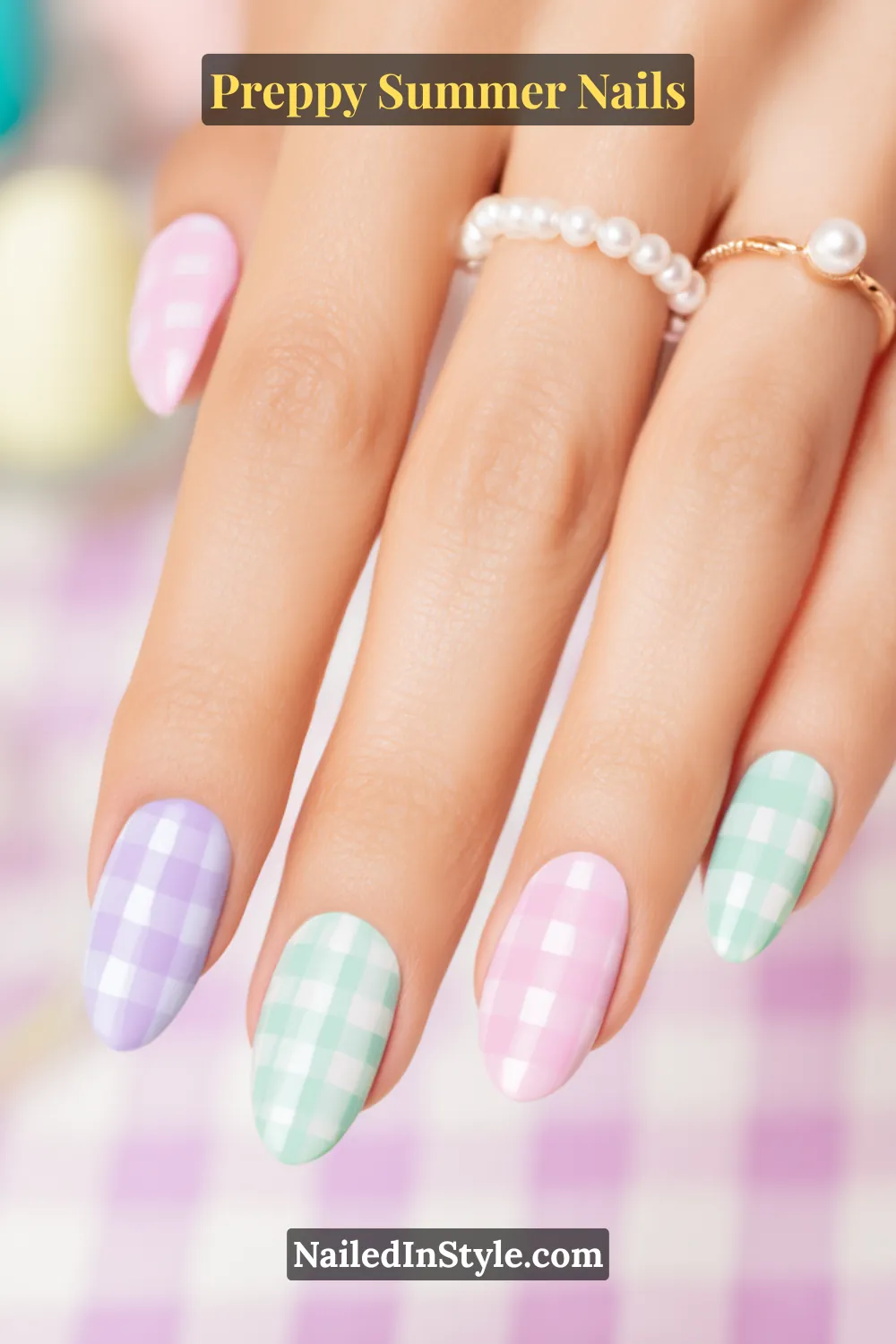 Hand with pastel summer nails featuring gingham check patterns in pink, mint, and lilac.