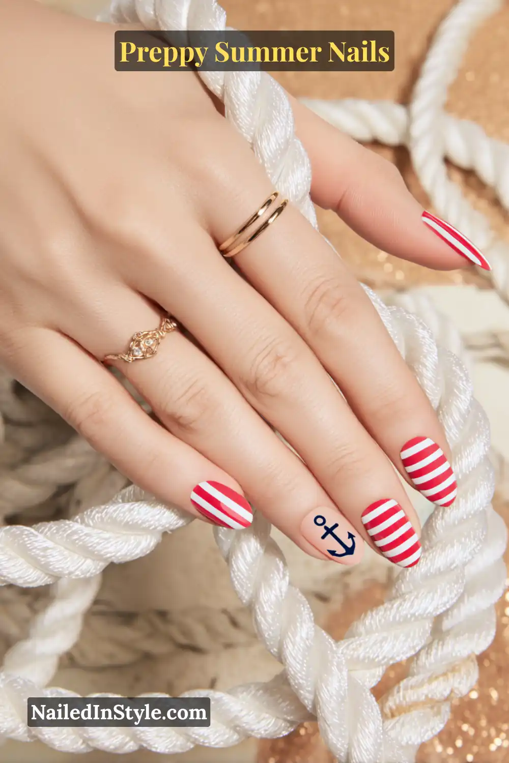 Hand with red and white striped nails featuring a navy anchor accent.