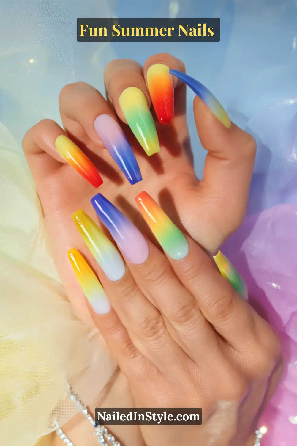 Hands with long coffin-shaped nails featuring a rainbow ombré gradient design blending vibrant red, orange, yellow, green, blue, and purple shades.