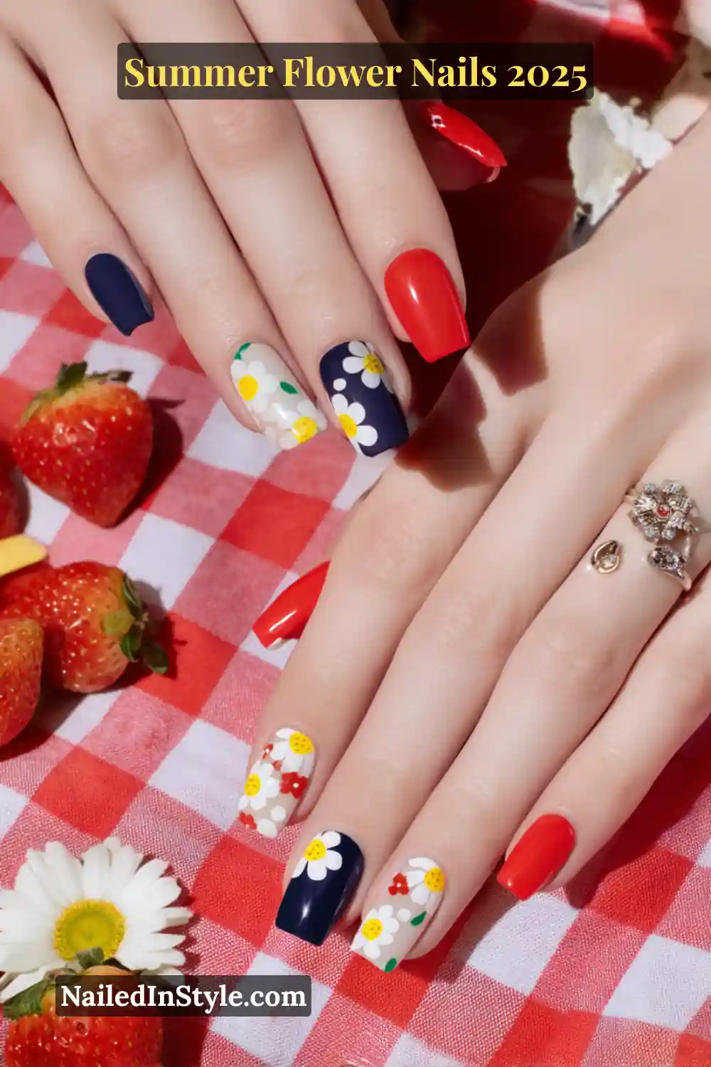 Square acrylic nails with bold red, navy, and white bases featuring pop-art-style daisy decals and a checkered picnic theme