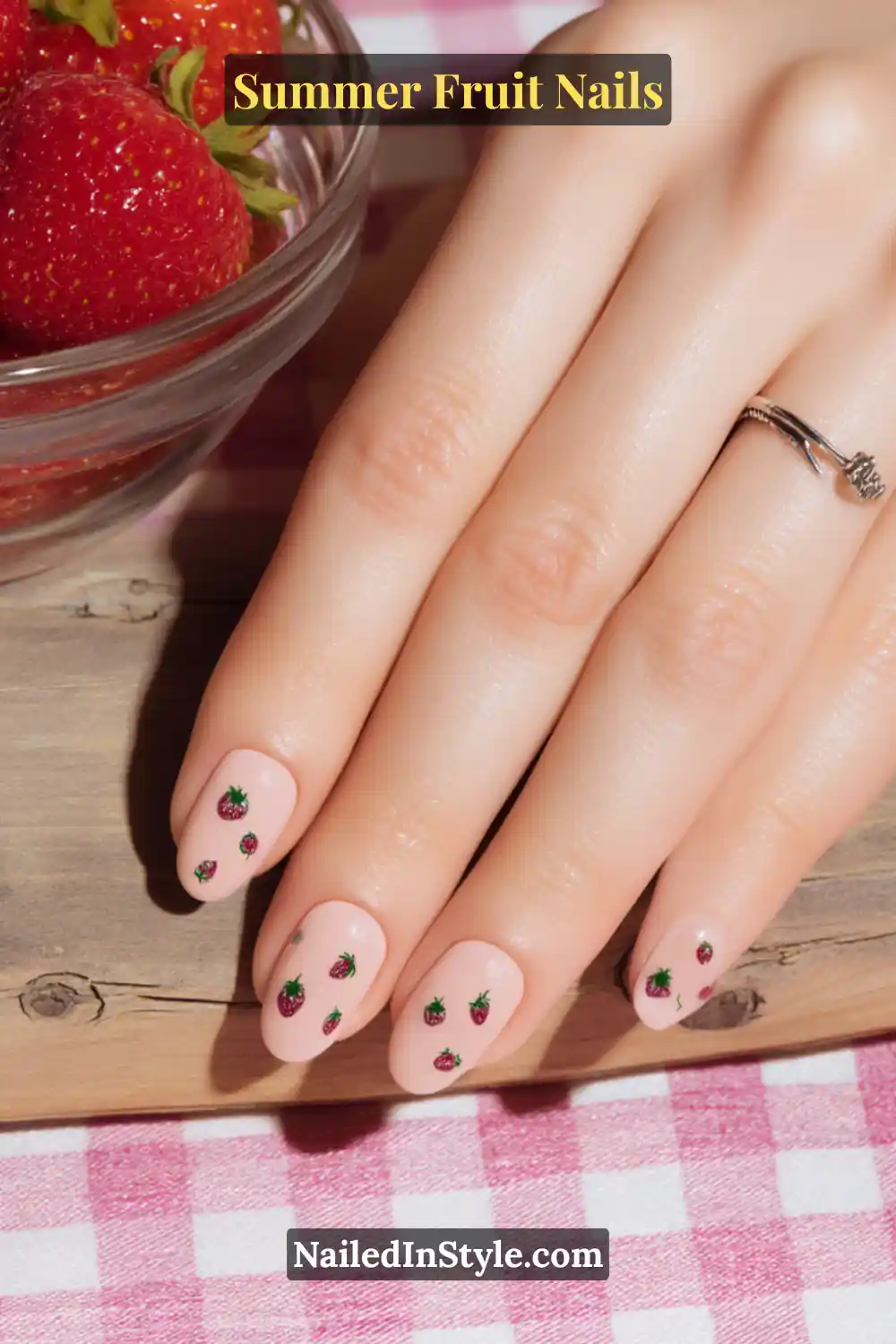 Light pink nails with tiny strawberry designs scattered across each nail.