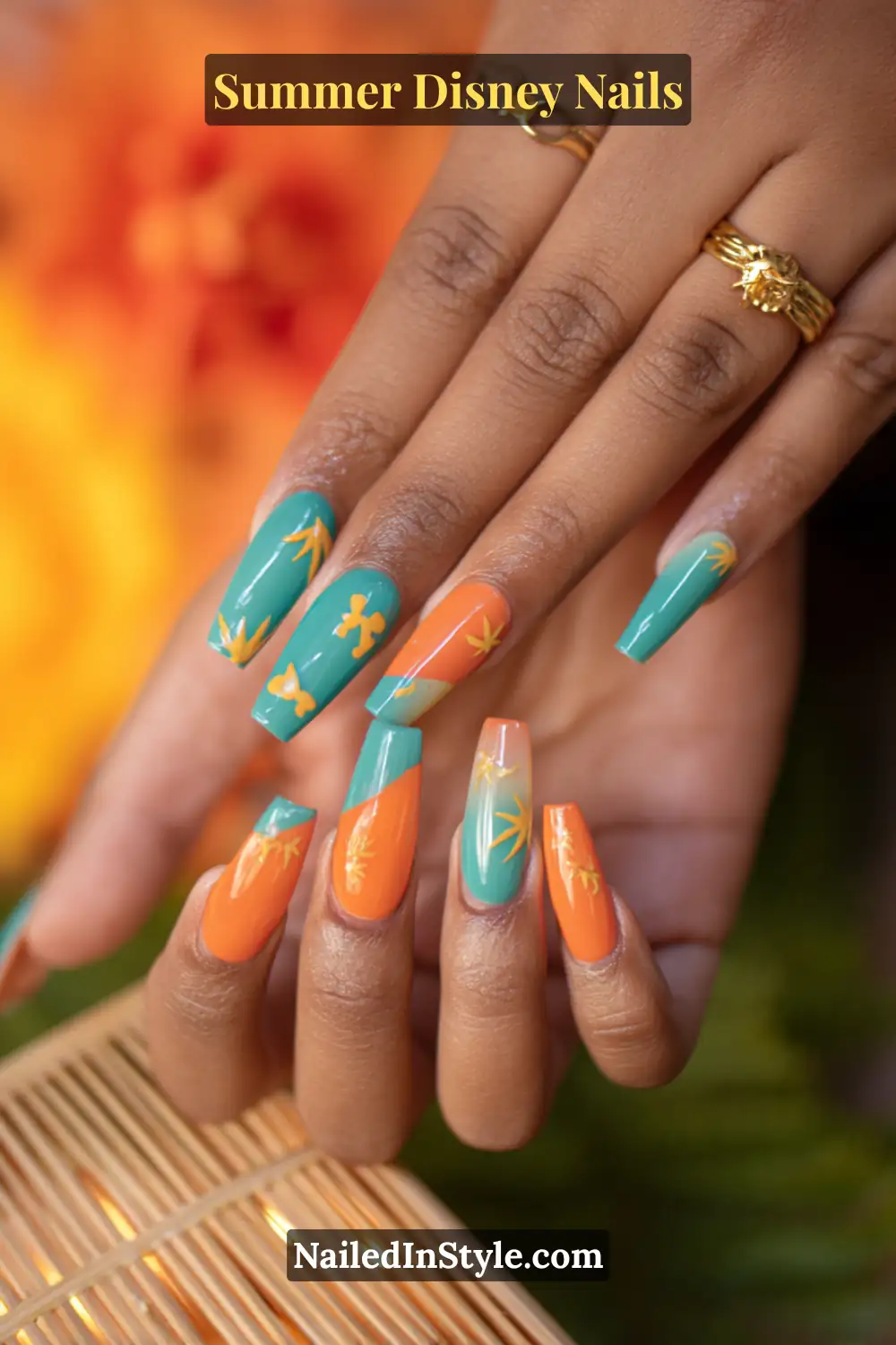 Long square nails in teal and sunset orange with tropical leaf and Mickey silhouette accents, glowing against tan skin.