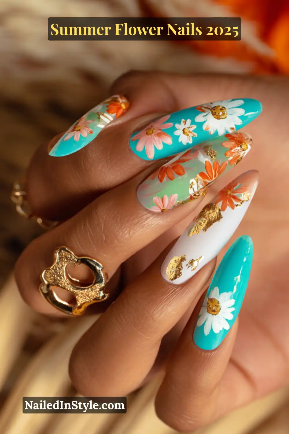 Bright floral nail art on tan skin with turquoise, white, orange petals, and gold foil accents.