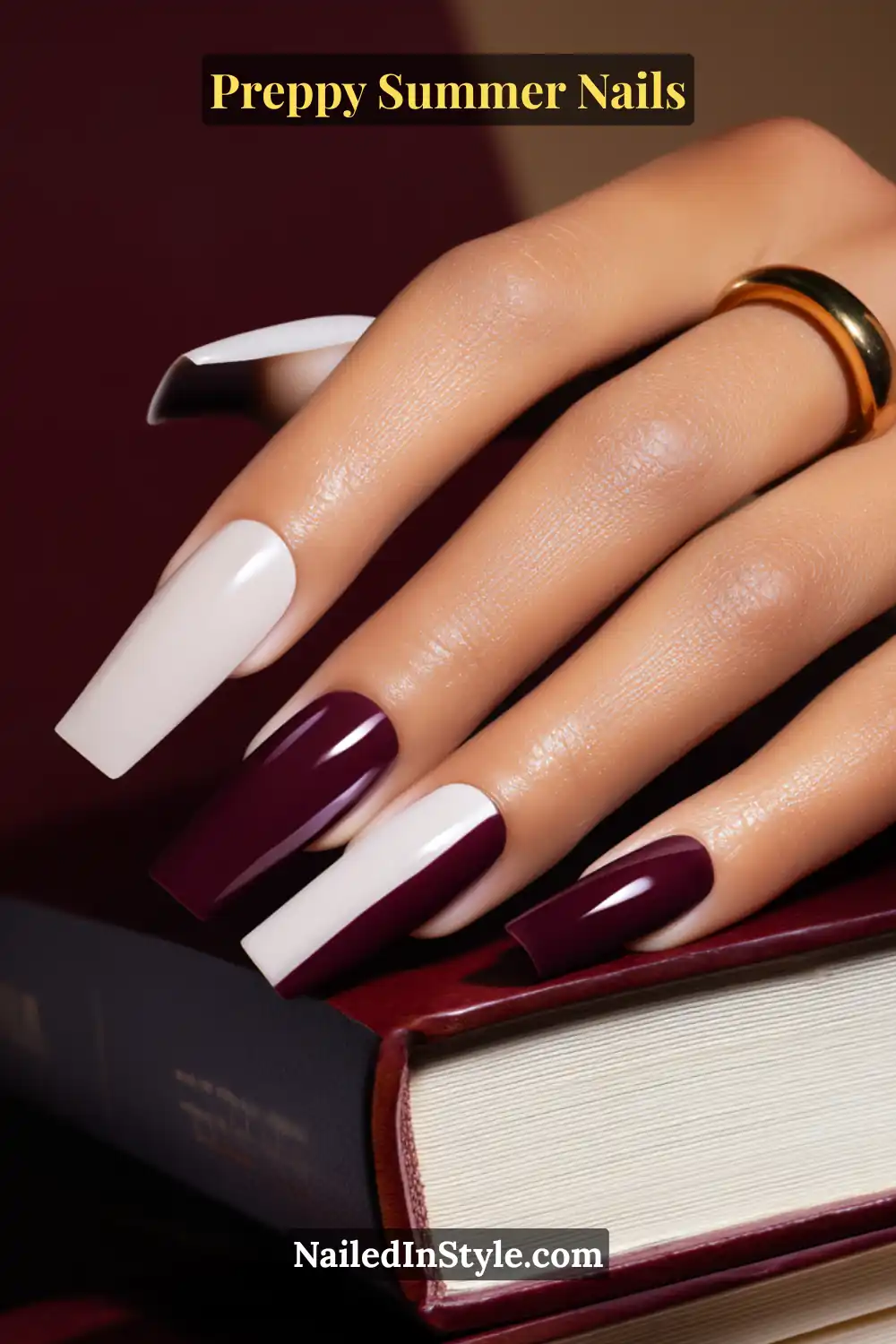 Hand with glossy burgundy and white summer nails on tan skin tone, styled with a gold ring.
