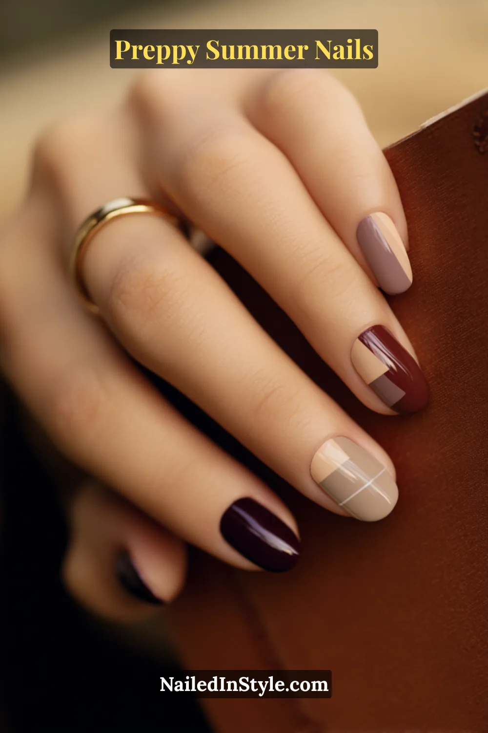 Hand with preppy summer nails in burgundy, beige, and taupe featuring plaid and geometric accent designs.