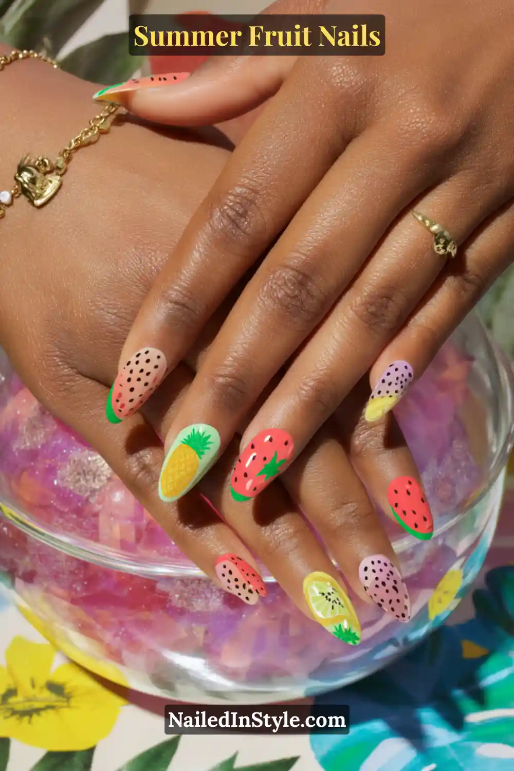 Almond-shaped nails each featuring a different fruit design—watermelon, pineapple, strawberry, dragon fruit, and kiwi—for a colorful, tropical look.