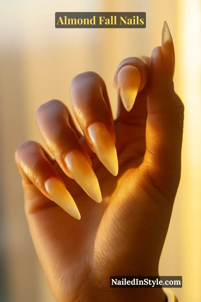 Almond nails with translucent amber jelly finish glowing in window light.