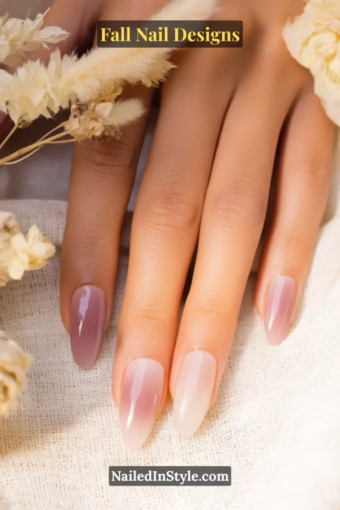 Hand with mauve and apricot airbrushed aura nails beside dried florals.