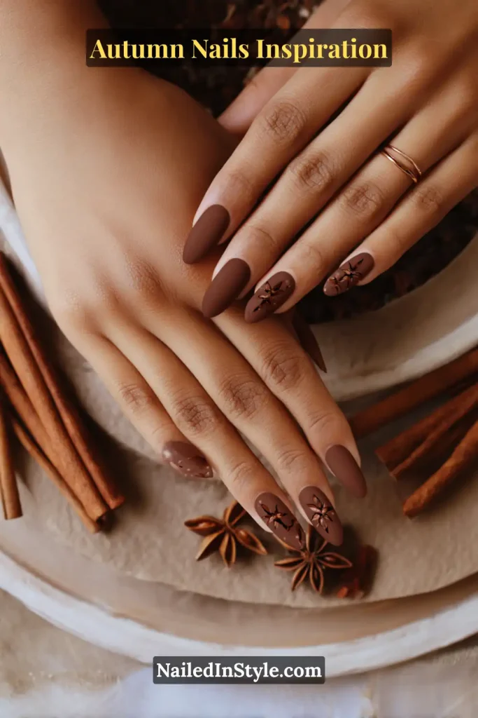 Matte cinnamon-brown nails with minimalist star anise stamps on accent fingers.
